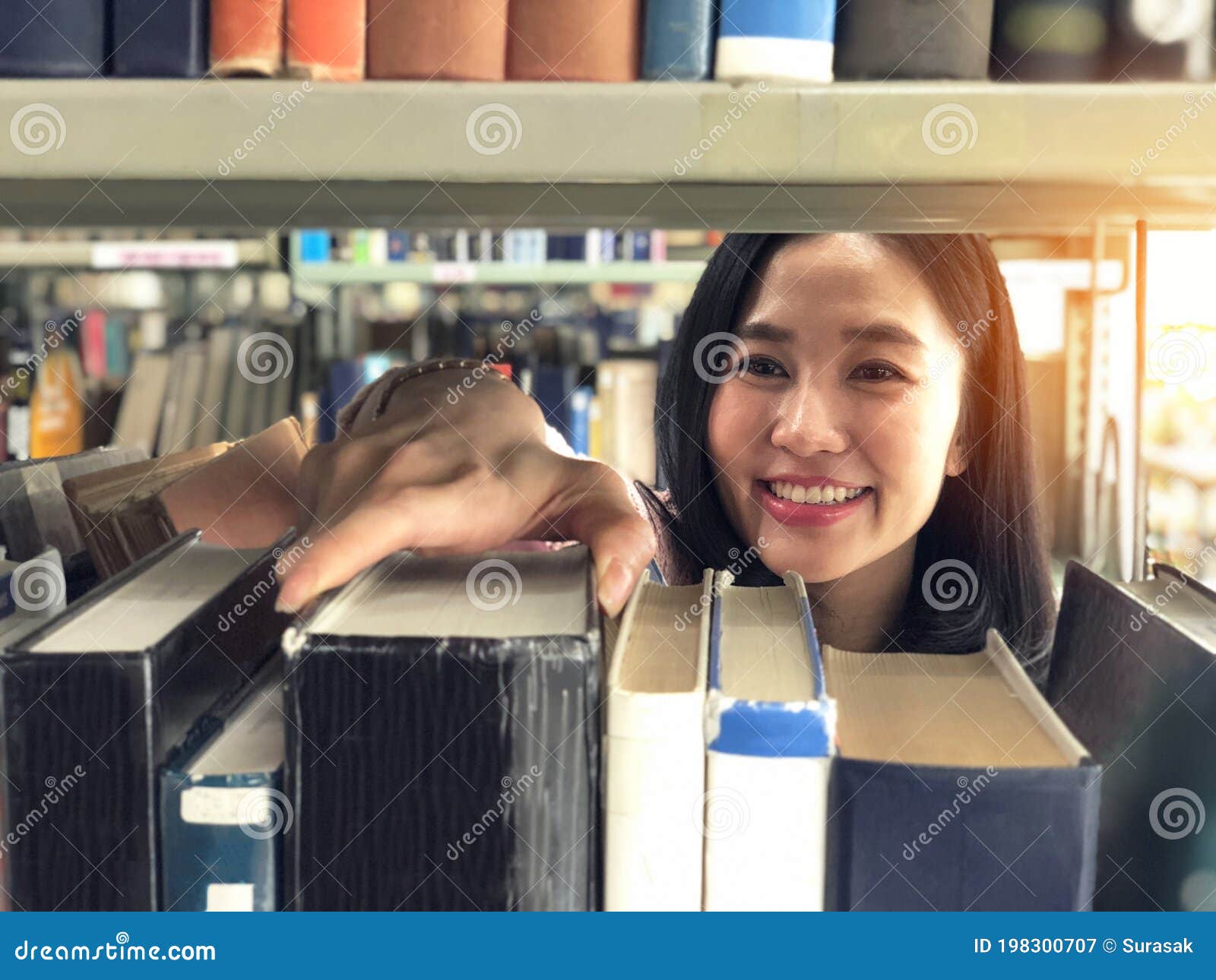 Young Woman Picking a Book Off the Shelf in a Library Stock Image