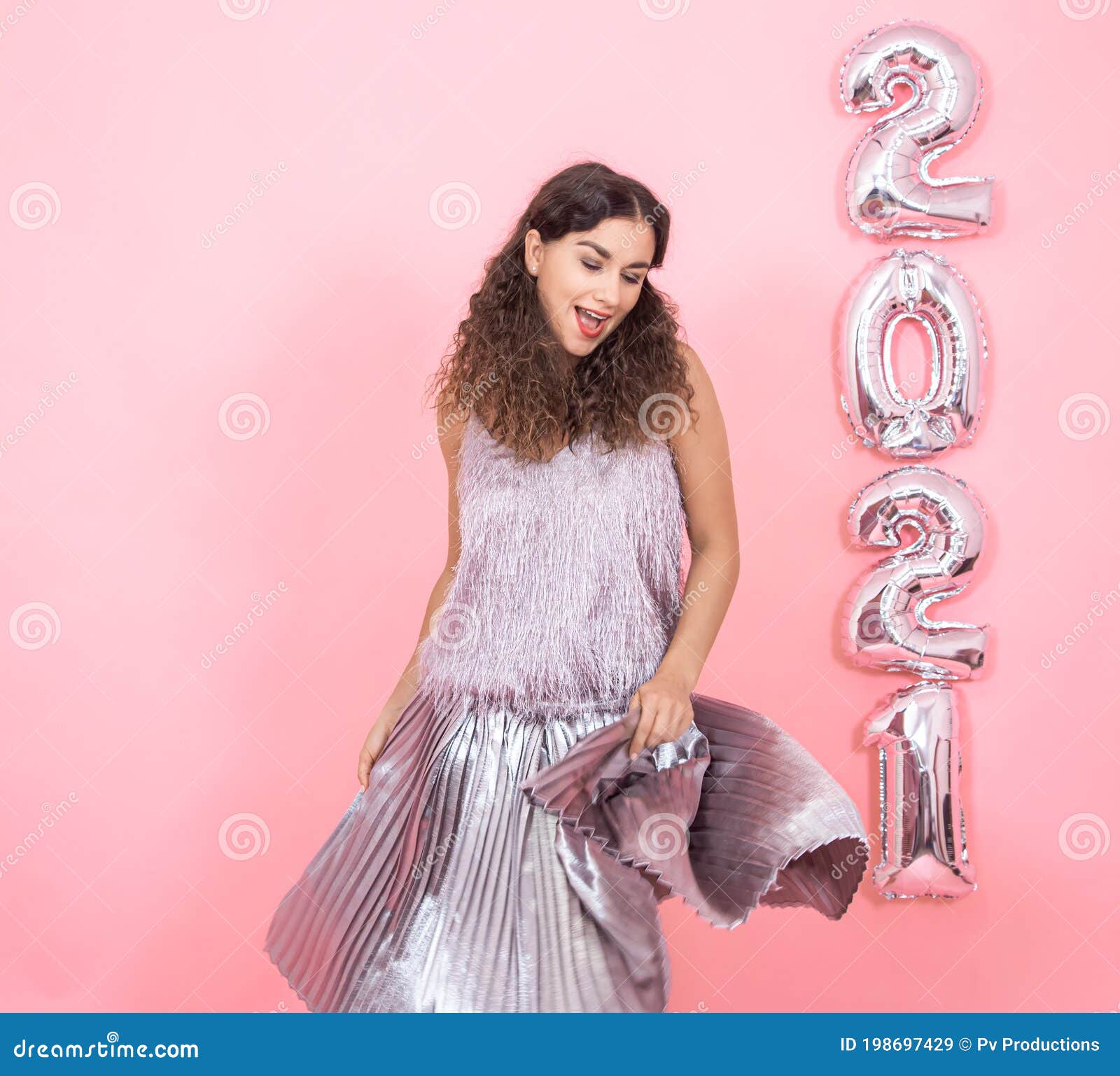 young woman on a pink background with silver balls in the form of the numbers 2021