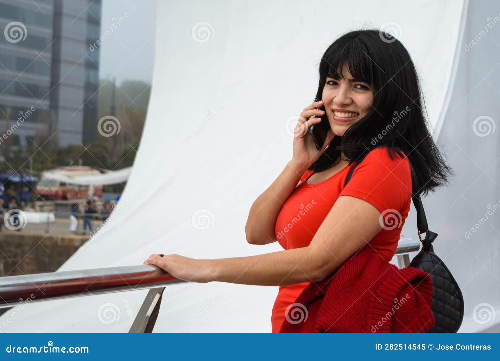 young woman at the puente de la mujer in buenos aires standing talking on the phone and smiling