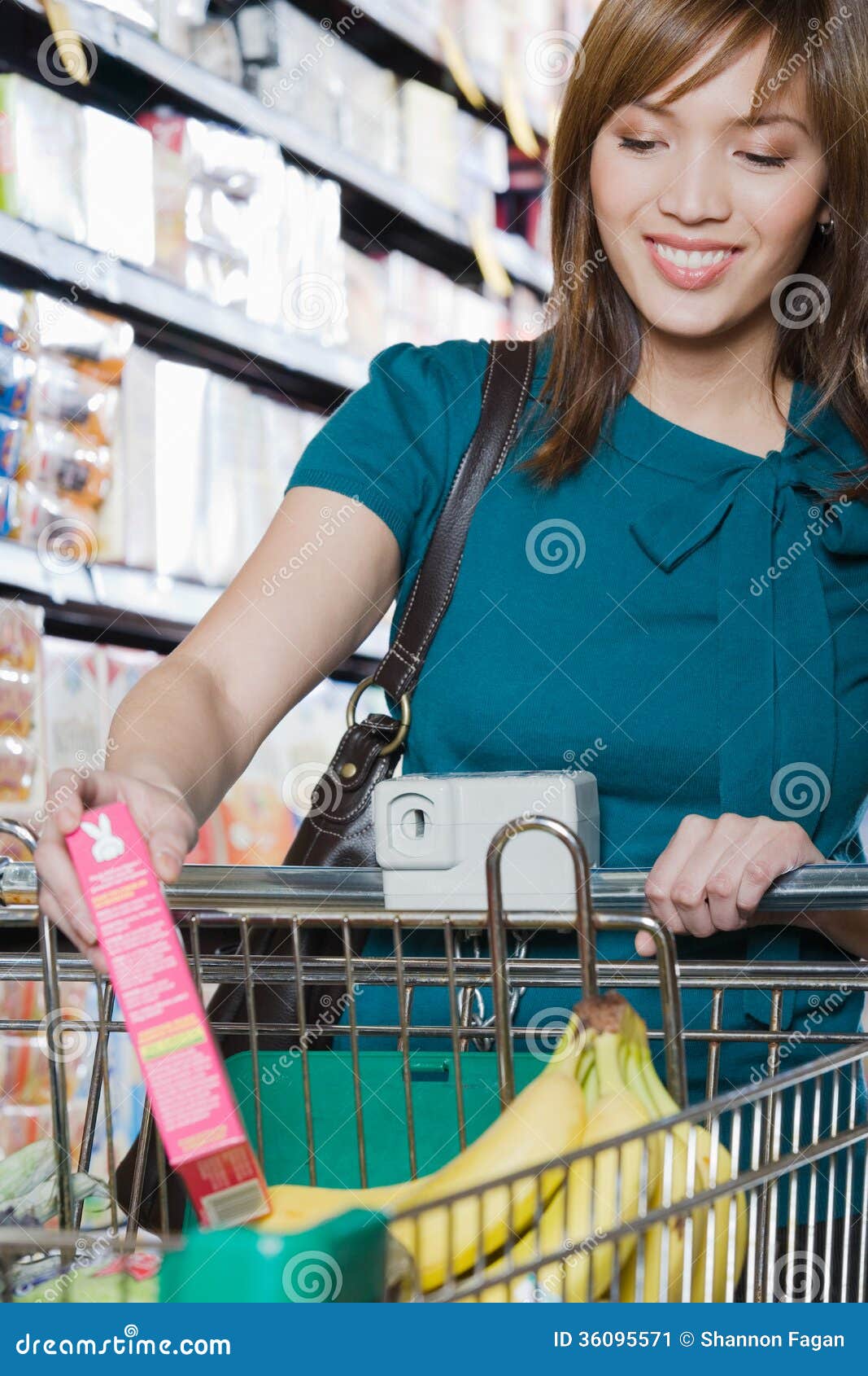 young woman putting a packet in a shopping trolley