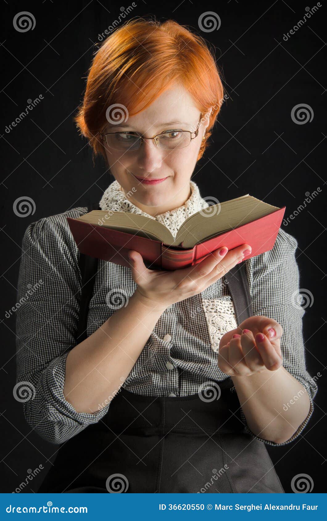 Young Woman Reading Book. Young woman with glasses reading a book against a black background