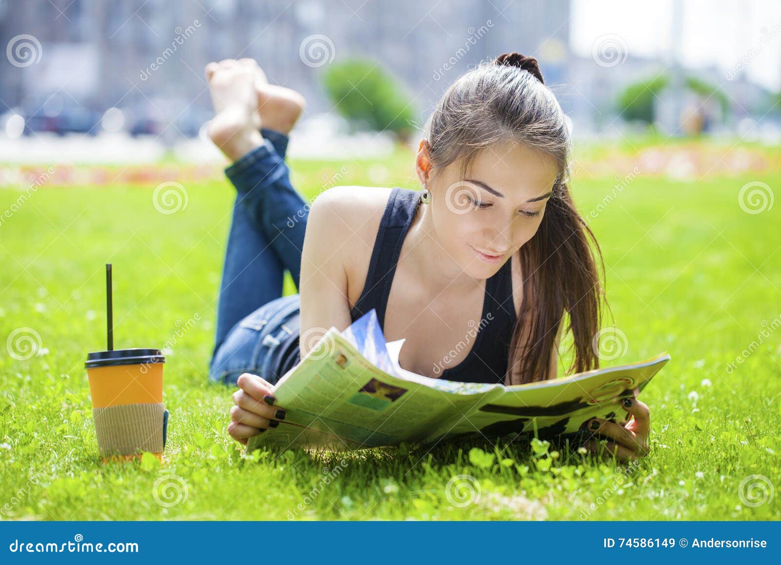 Young woman reading magazine lying on grass