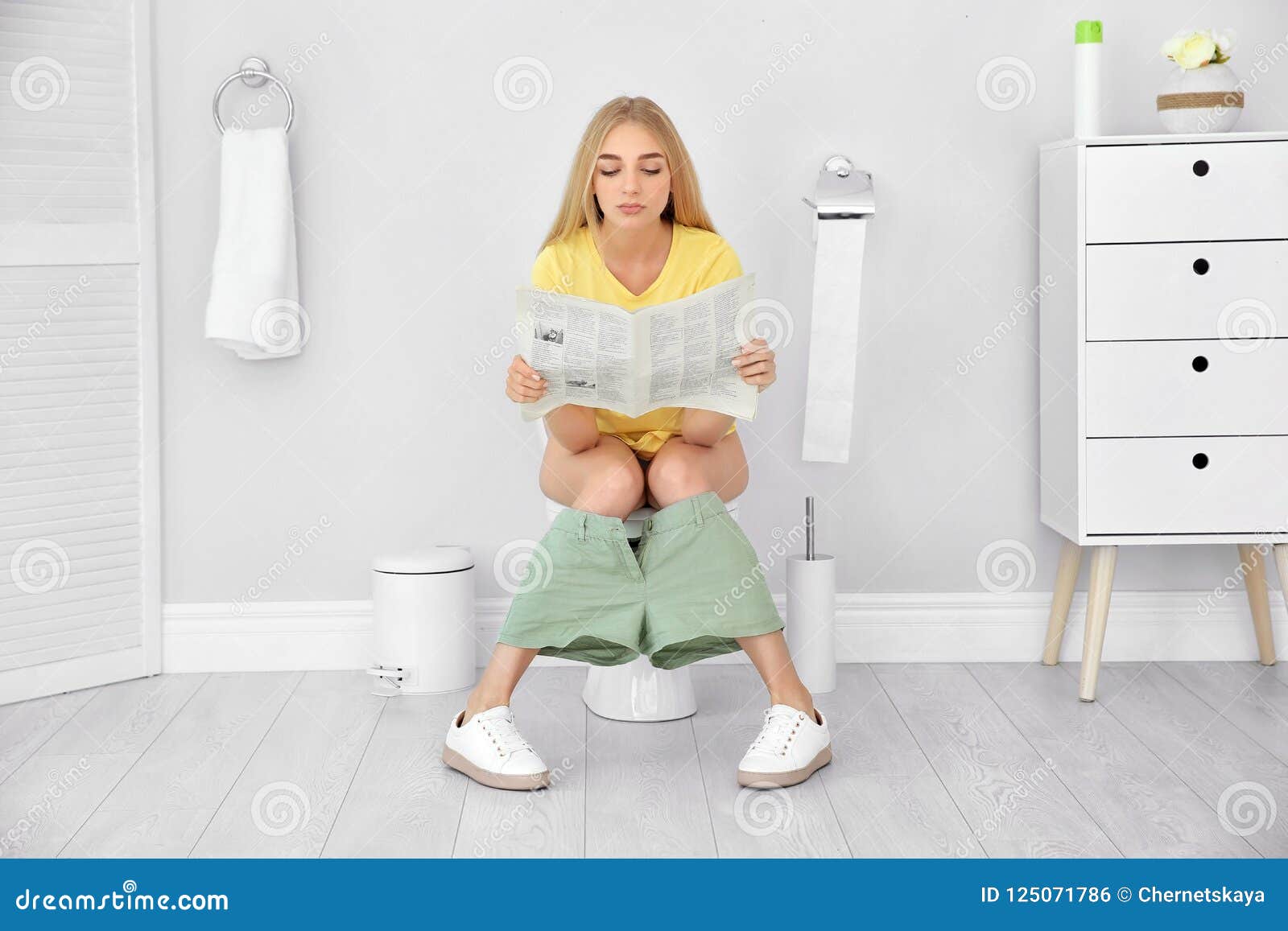 Young Woman Reading Newspaper While Sitting On Toilet Stock Photo - Image o...