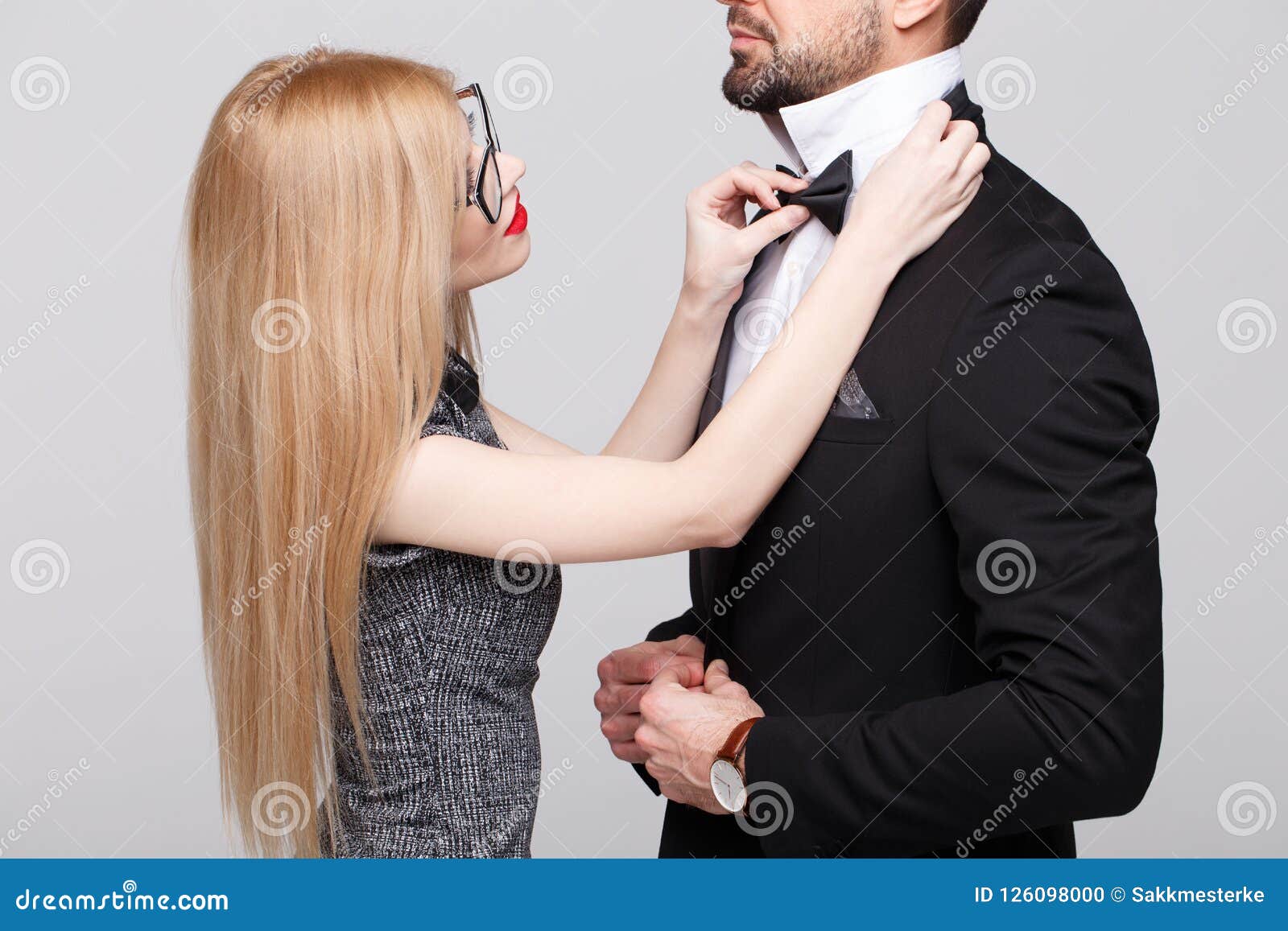 young woman with red lips straighten man bow tie