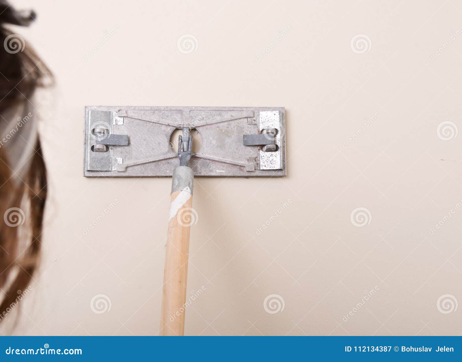 Young Woman Is Sanding Wall With Pole Sander Before Painting Stock