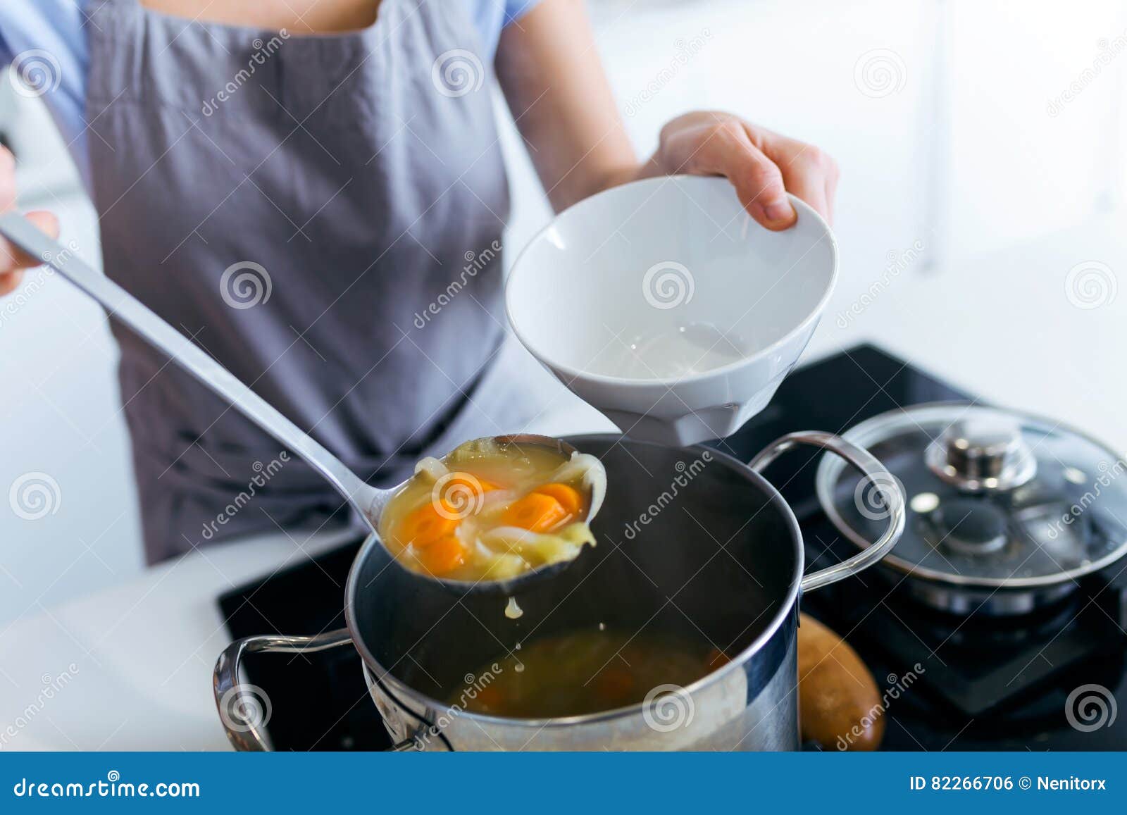 Young Woman Serving Vegetable Soup in the Kitchen. Stock Photo Image
