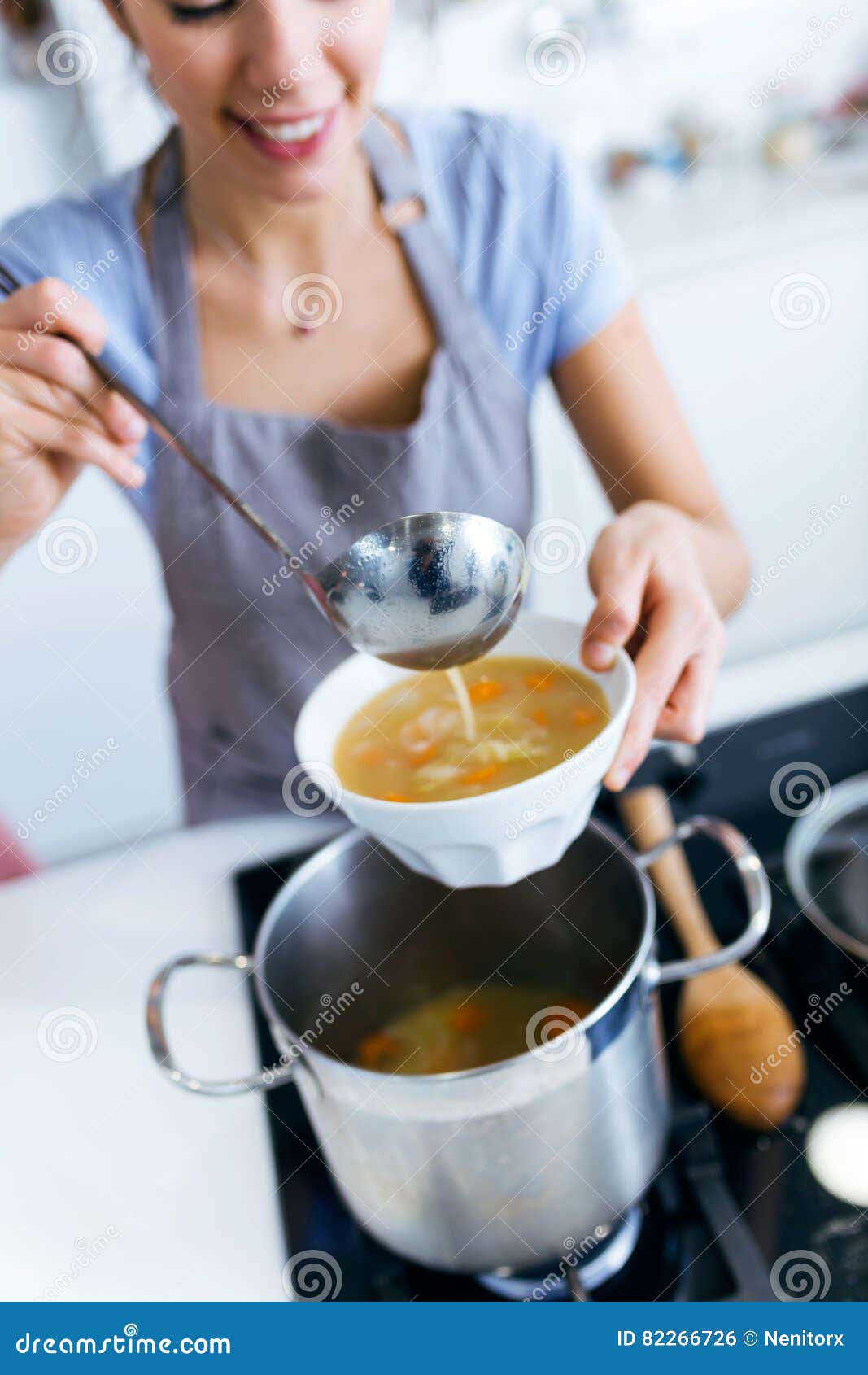 Young Woman Serving Vegetable Soup in the Kitchen. Stock Photo Image