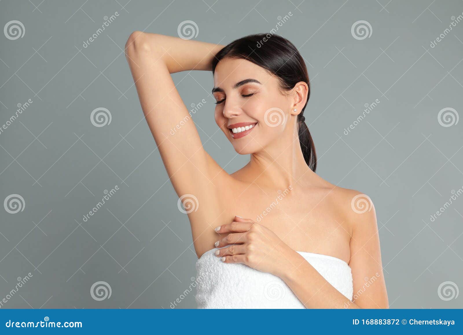 young woman showing hairless armpit after epilation procedure on background