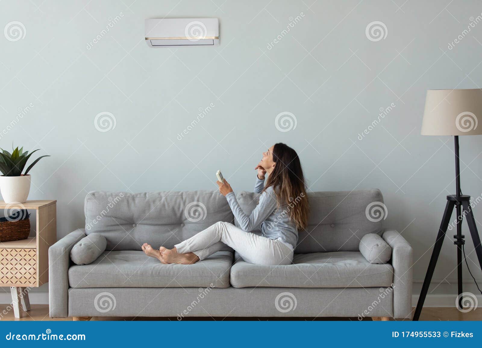young woman turn on air conditioner in living room