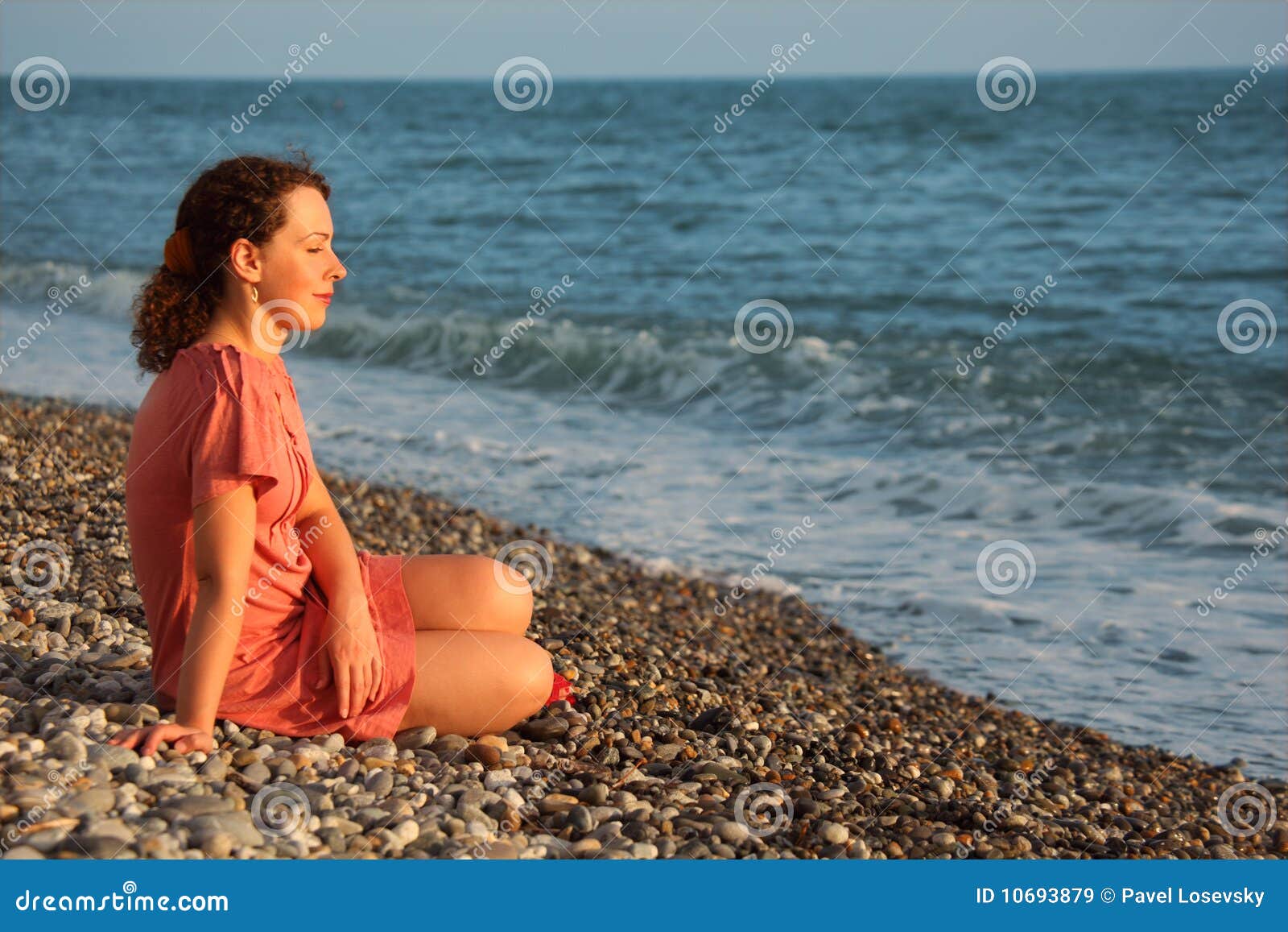 young woman sits ashore of sea