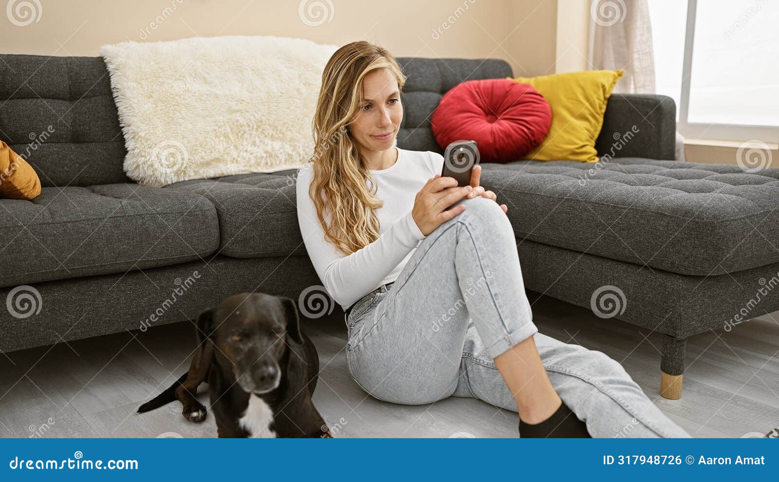 a young woman sitting on the floor using her phone with a black dog beside her in a cozy living room