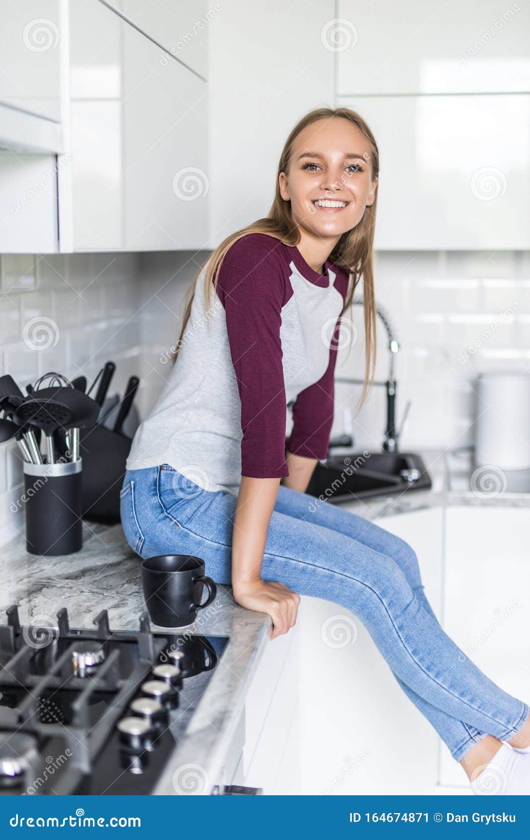 Young Pretty Woman Sitting On Kitchen Counter At Home Stock Image