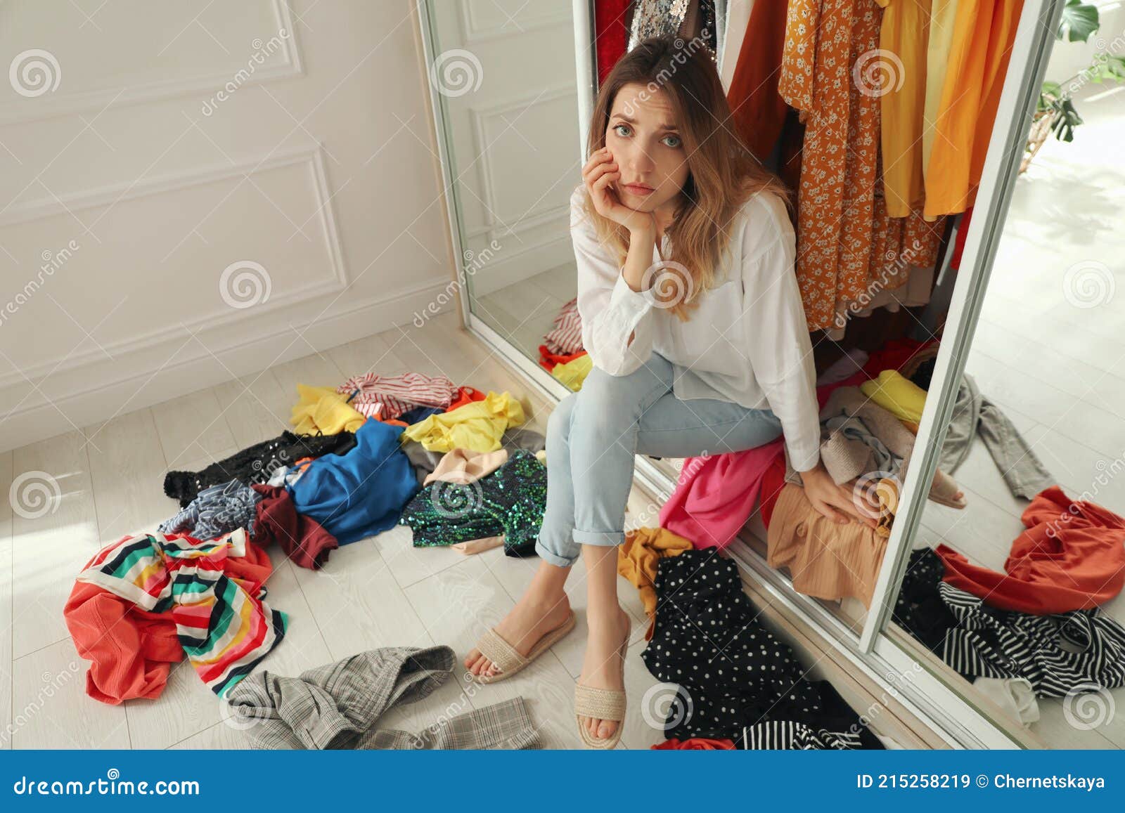 Young Woman Sitting In Wardrobe With Different Clothes Indoors Fast Fashion Concept Stock Image