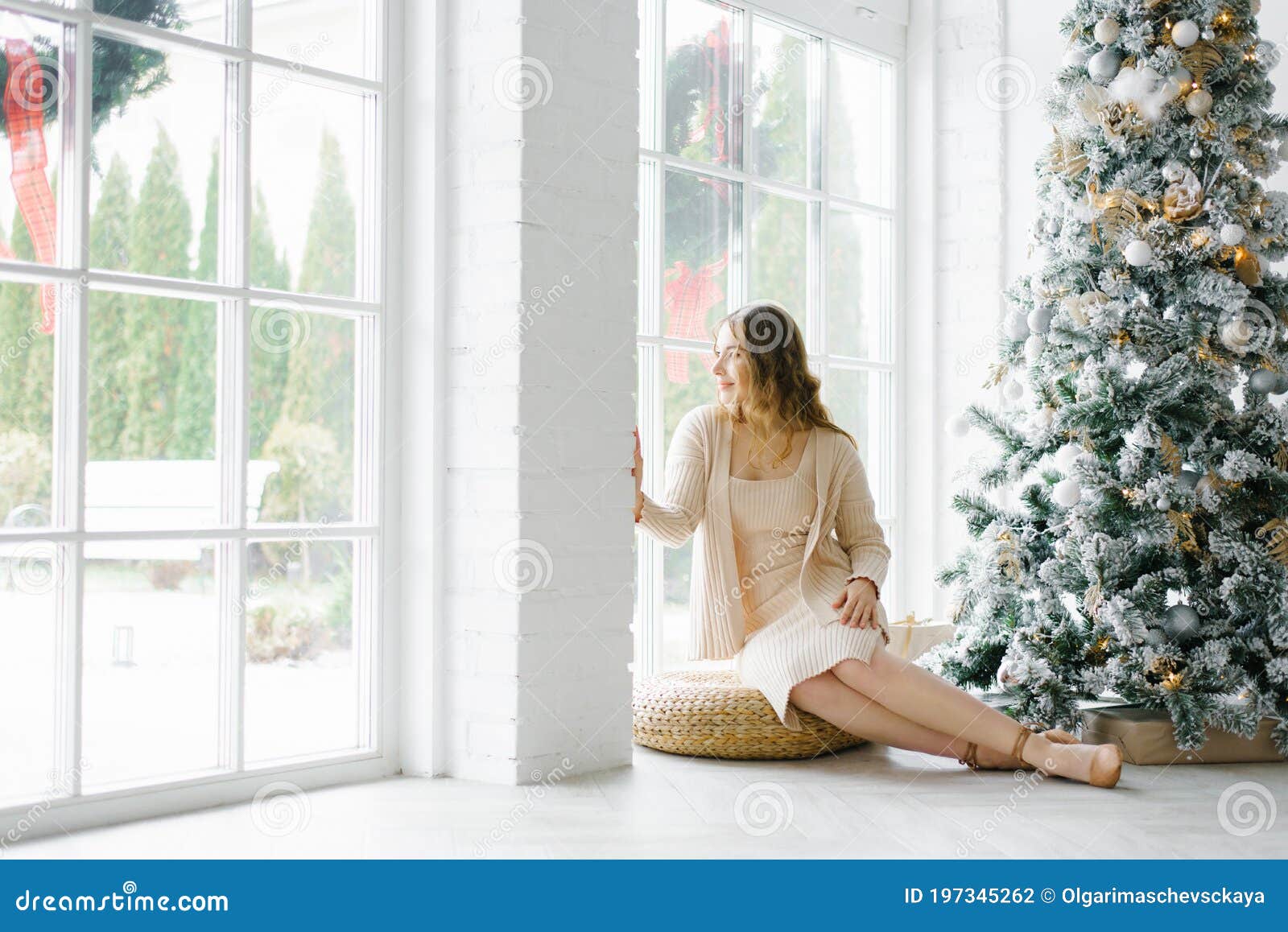 A Young Woman in a Spacious Living Room with Christmas Decor Sits ...