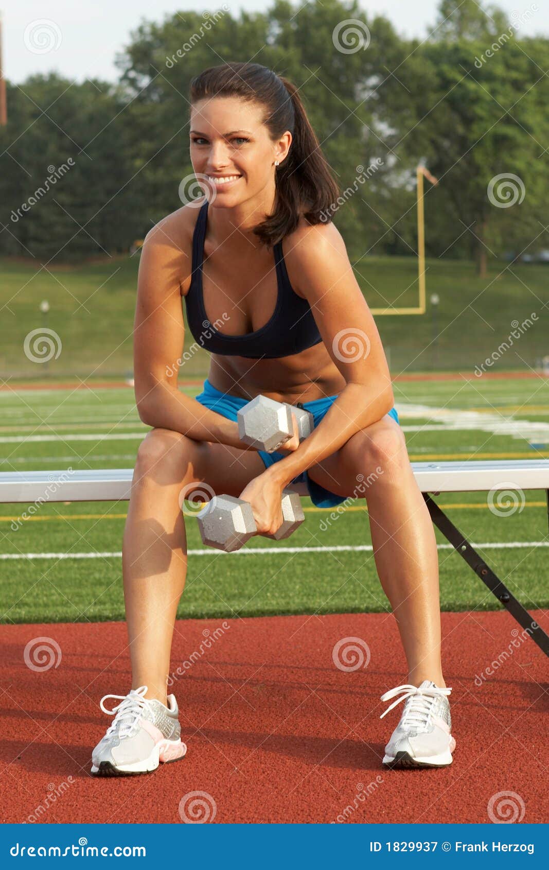 Young Woman in Sports Bra Holding Dumbbells on Bench Stock Image