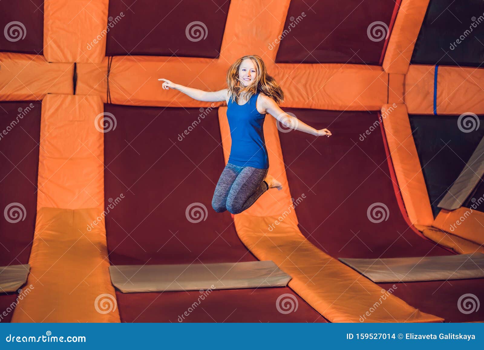 young woman sportsman jumping on a trampoline in fitness park and doing exersice indoors