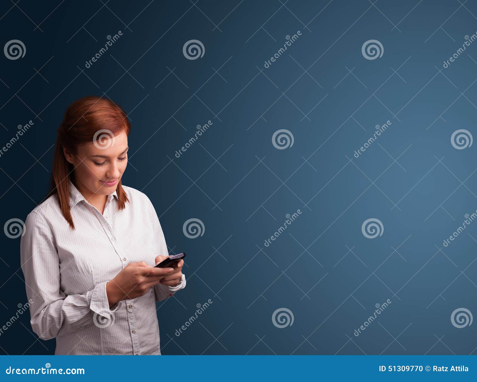 Pretty young woman standing and typing on her phone with copy space