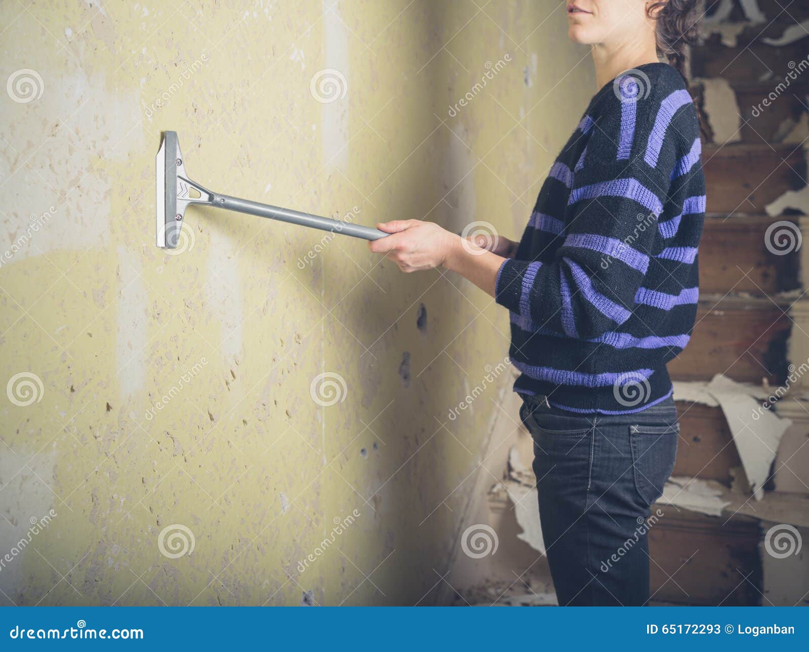 young woman stripping wallpaper