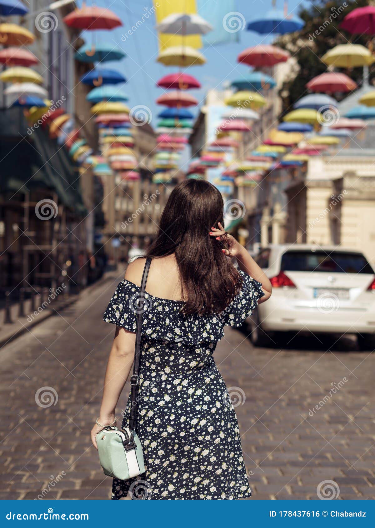 Young Woman in Stylish Dress Walking Down the Street Alone