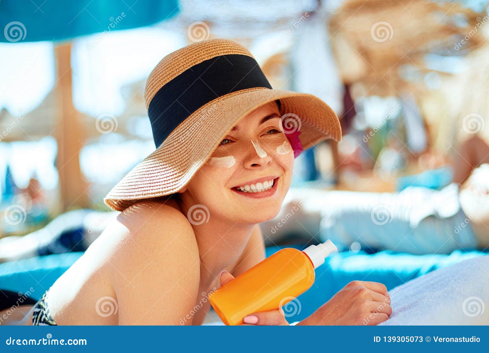 Young Woman with Sun Cream on Face Holding Sunscreen Bottle on the ...