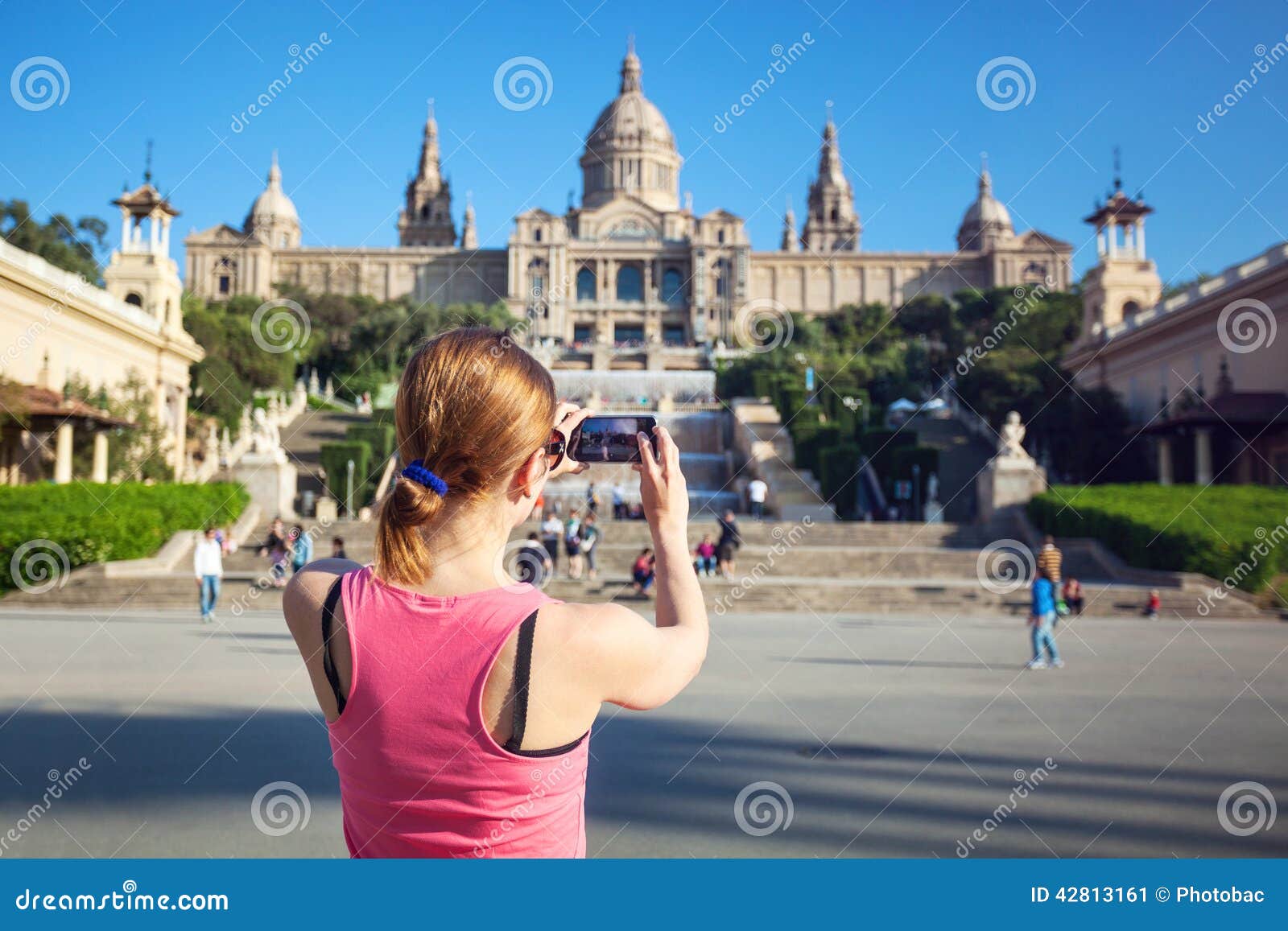 young woman taking picture of catalan art museum (mnac)