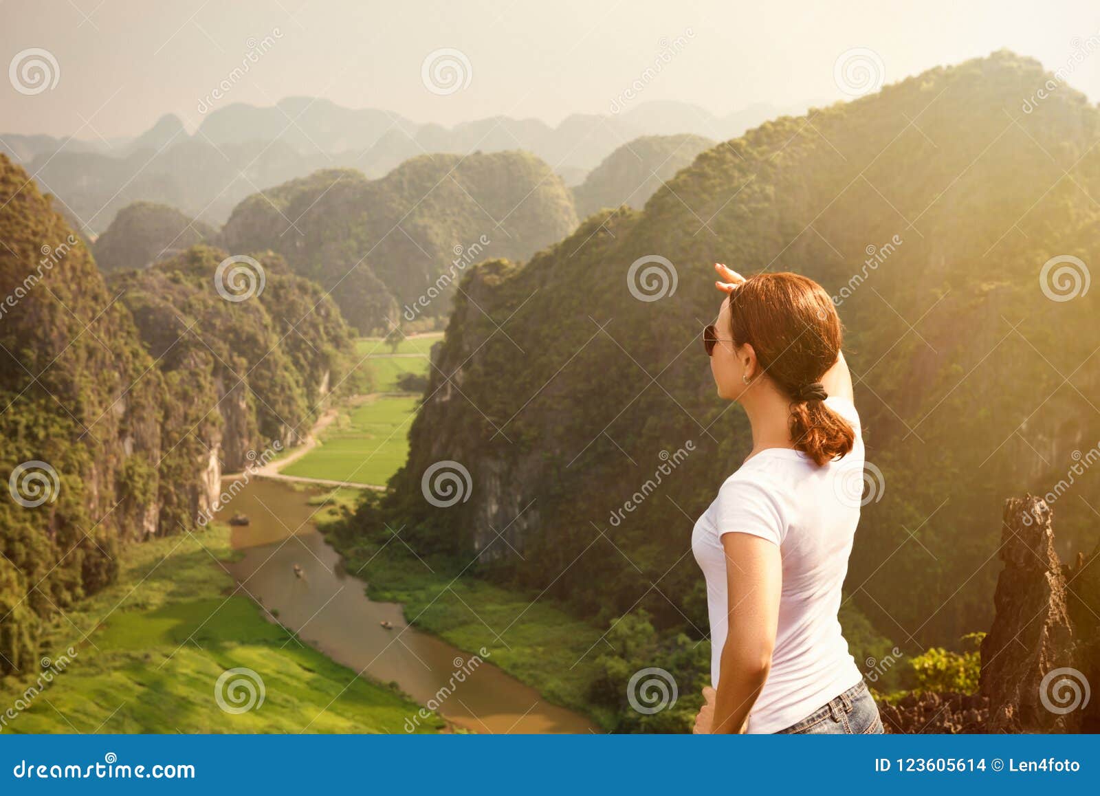 woman tourist looking far away and enjoying valley and hills view from top of a mountain