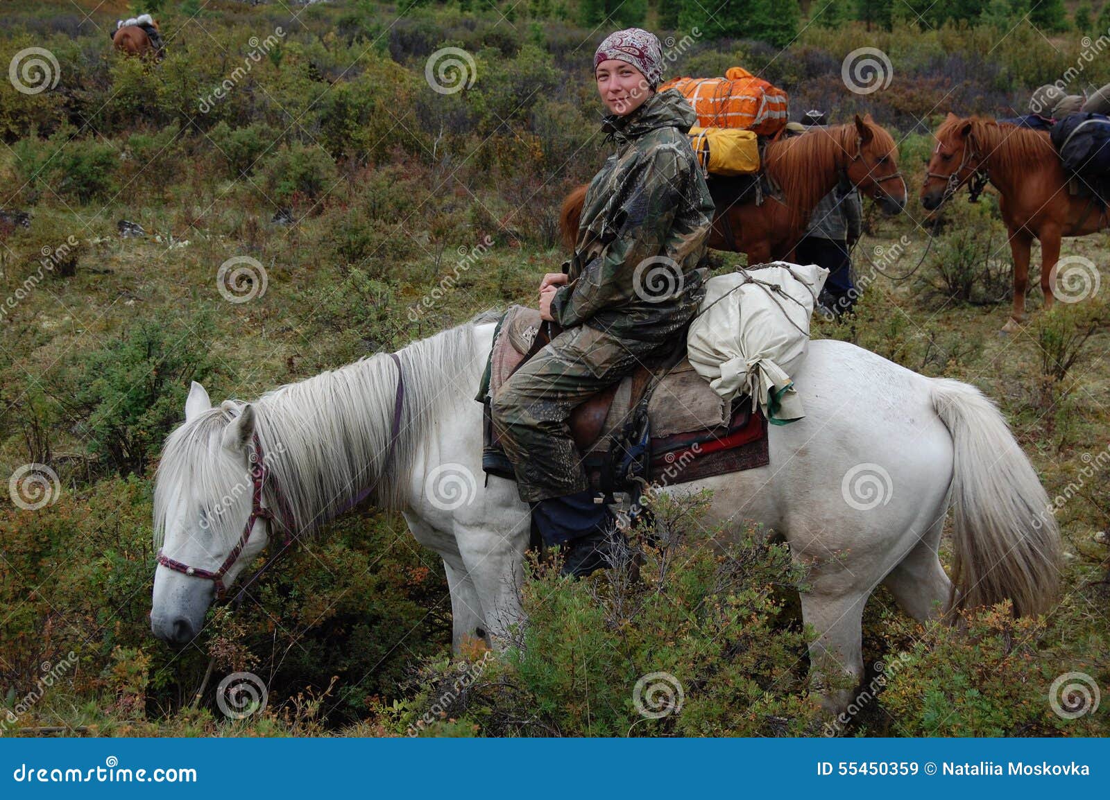 young woman travels through the moutnains on horseback.