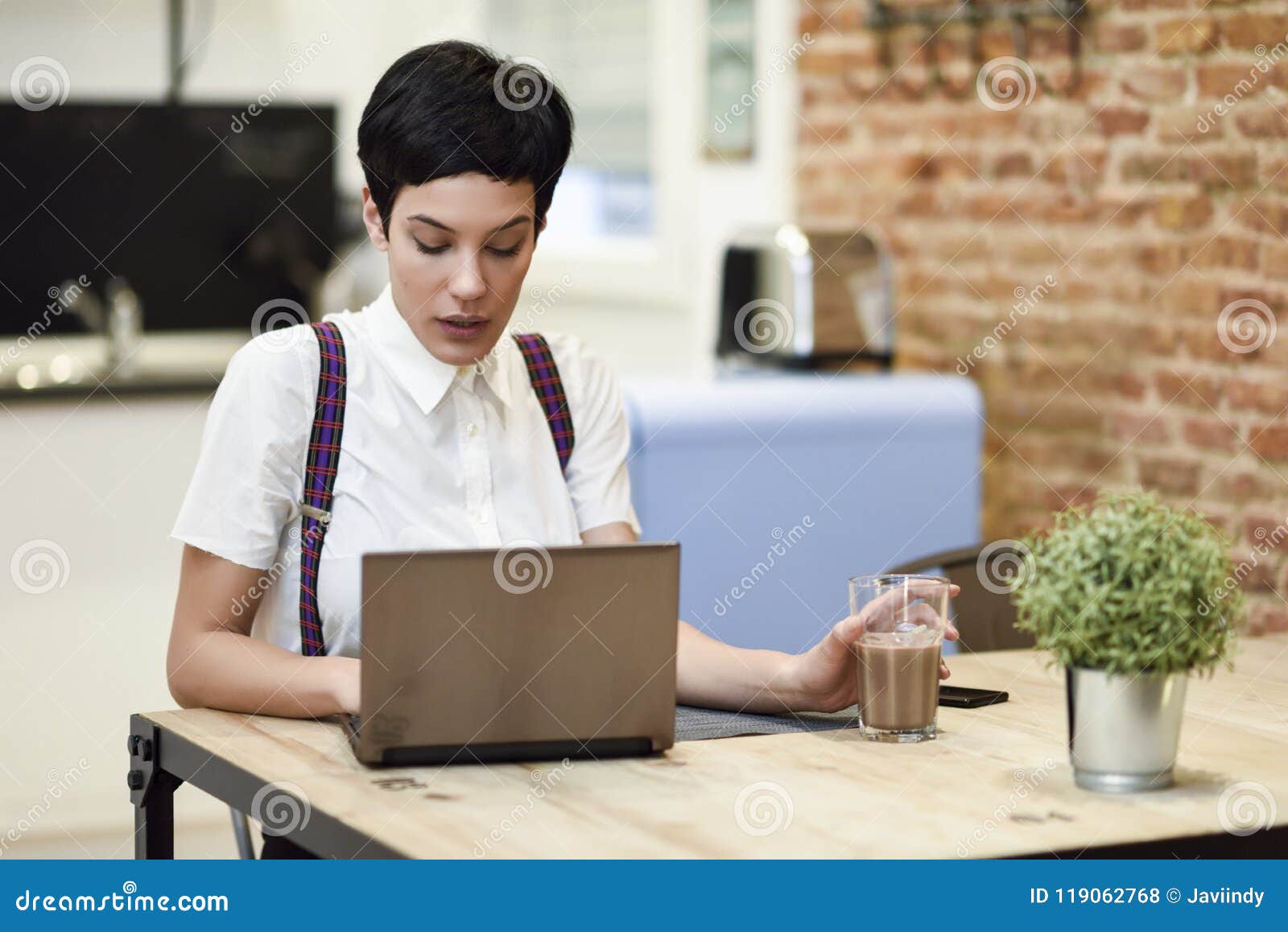 Young Woman with Very Short Haircut Typing with a Laptop at Home Stock