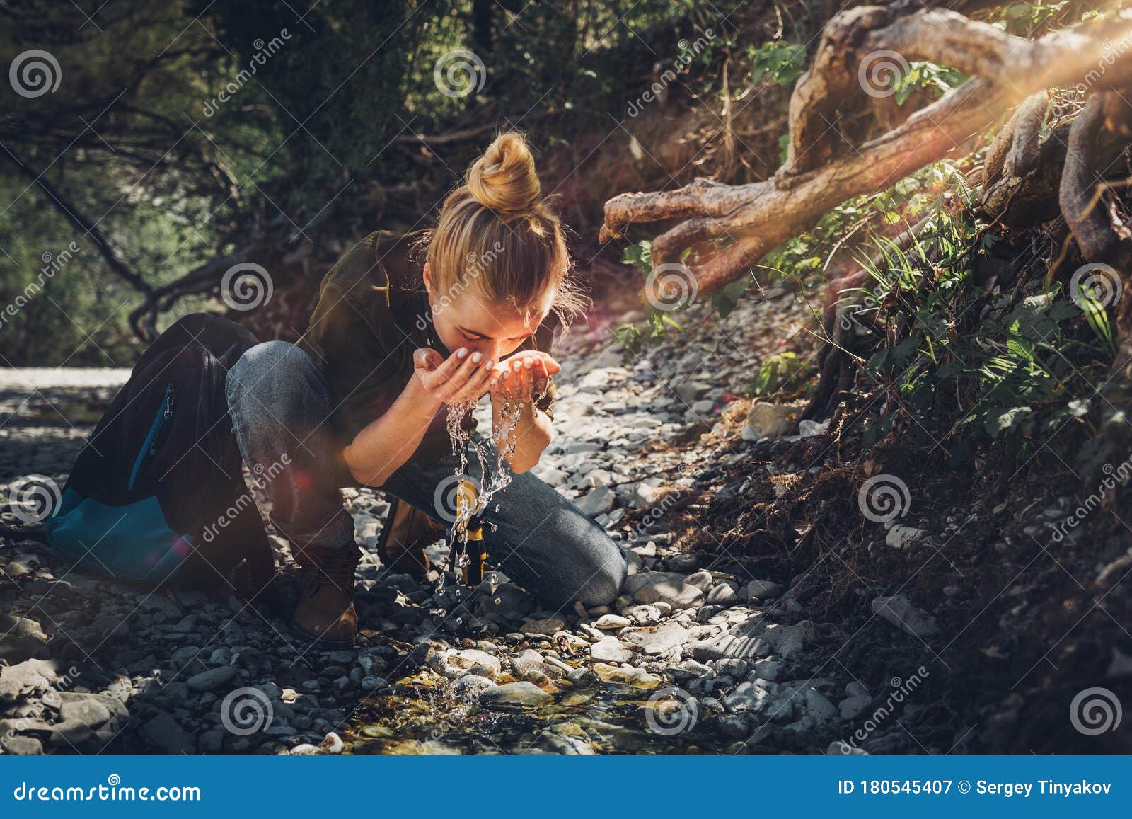 young woman washes her face from mountain river. tourism adventure bushcraft survival scout concept