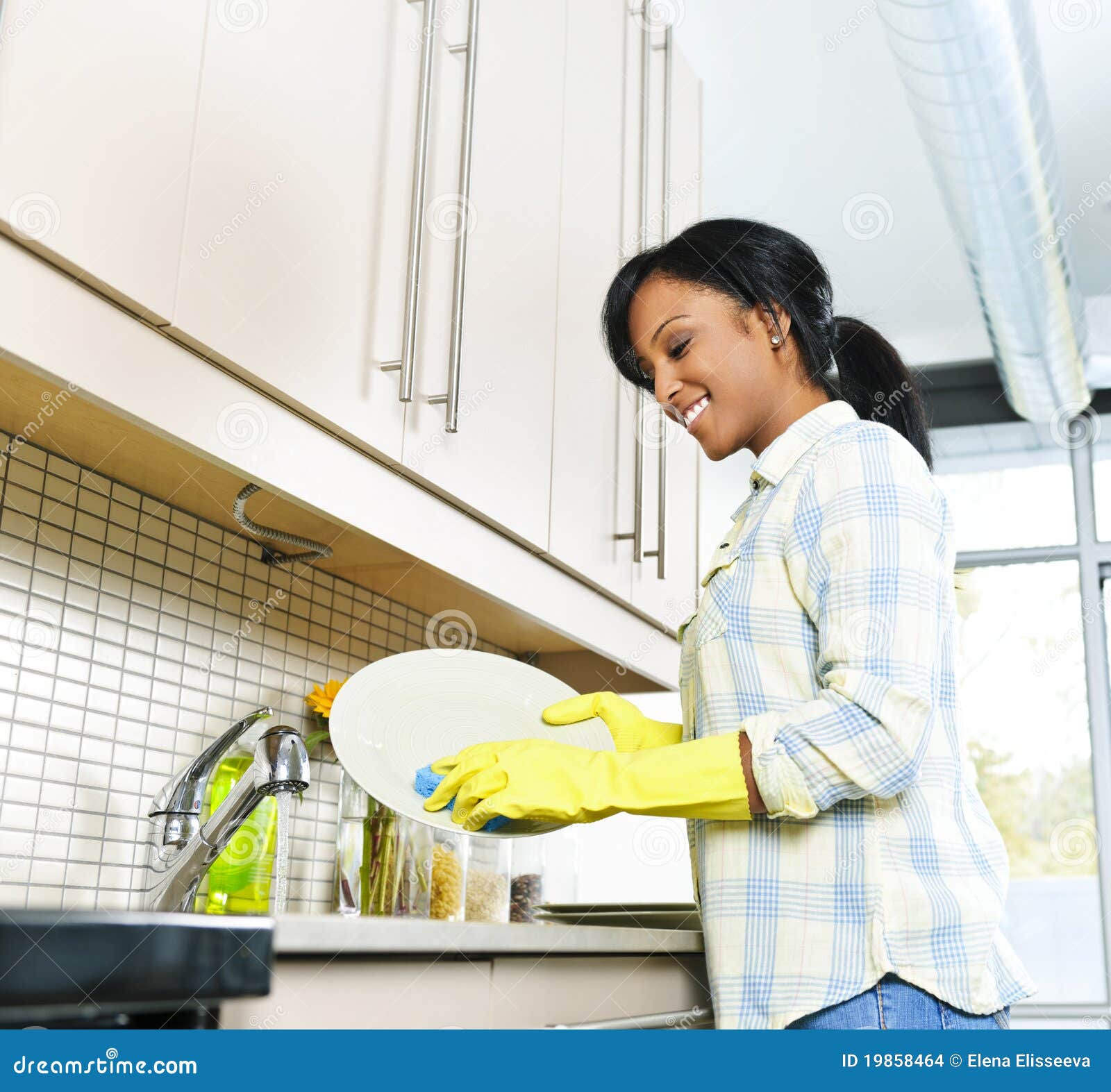 Portrait of a smiling young woman washing dishes Stock Photo by vadymvdrobot