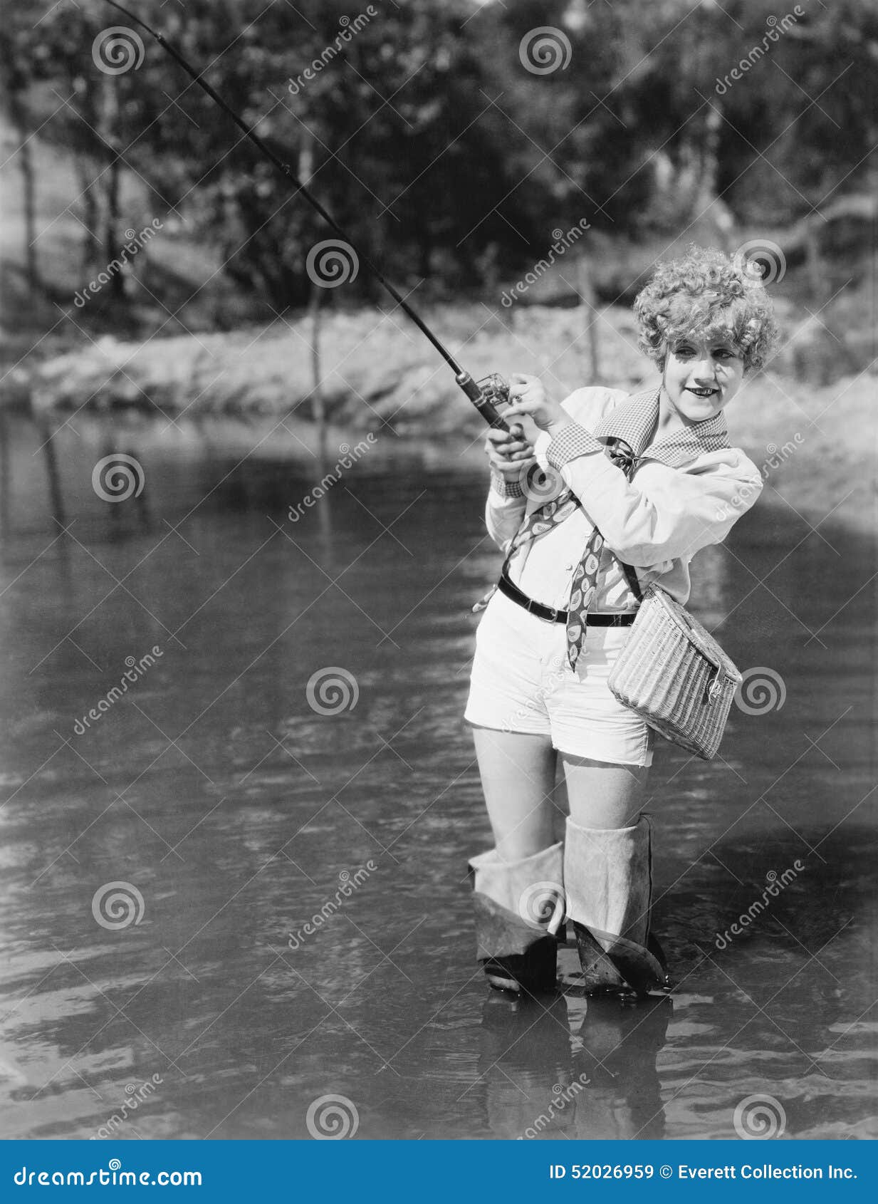 young woman wearing waders holding a fishing rod