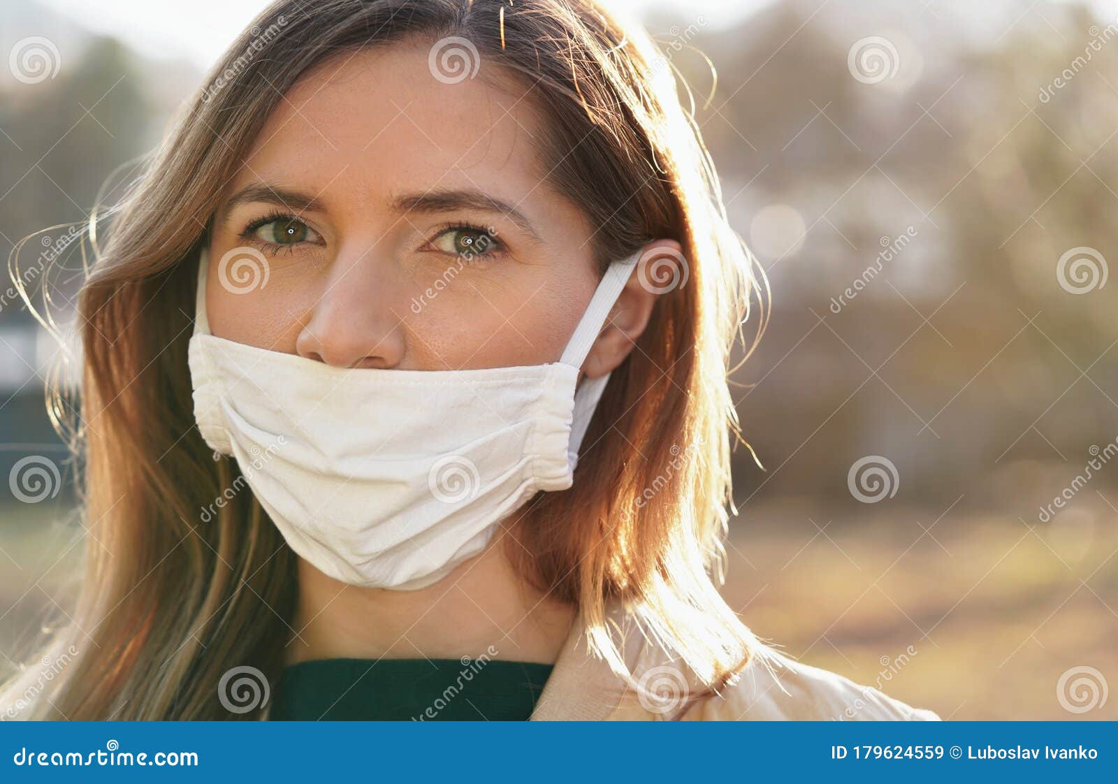 young woman wears home made white cotton mouth face mask, wrong way, incorrect wearing - masks should cover nose as well