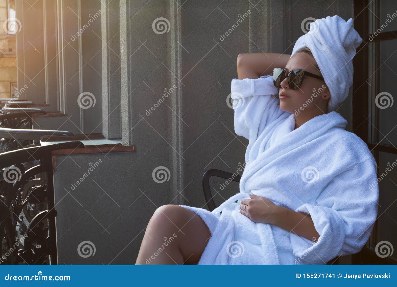 Young Woman in a White Bathrobe, Hair Towel and Sunglasses Sitting in a ...