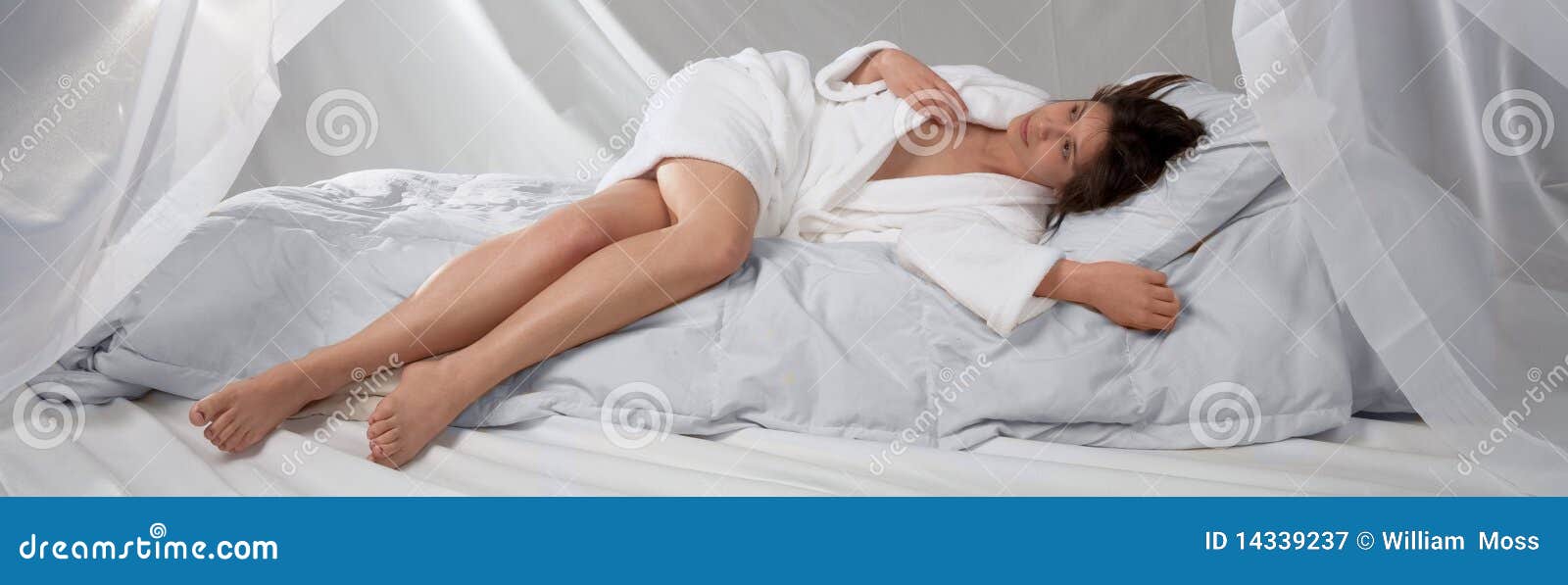 young woman in white bathrobe on white bed