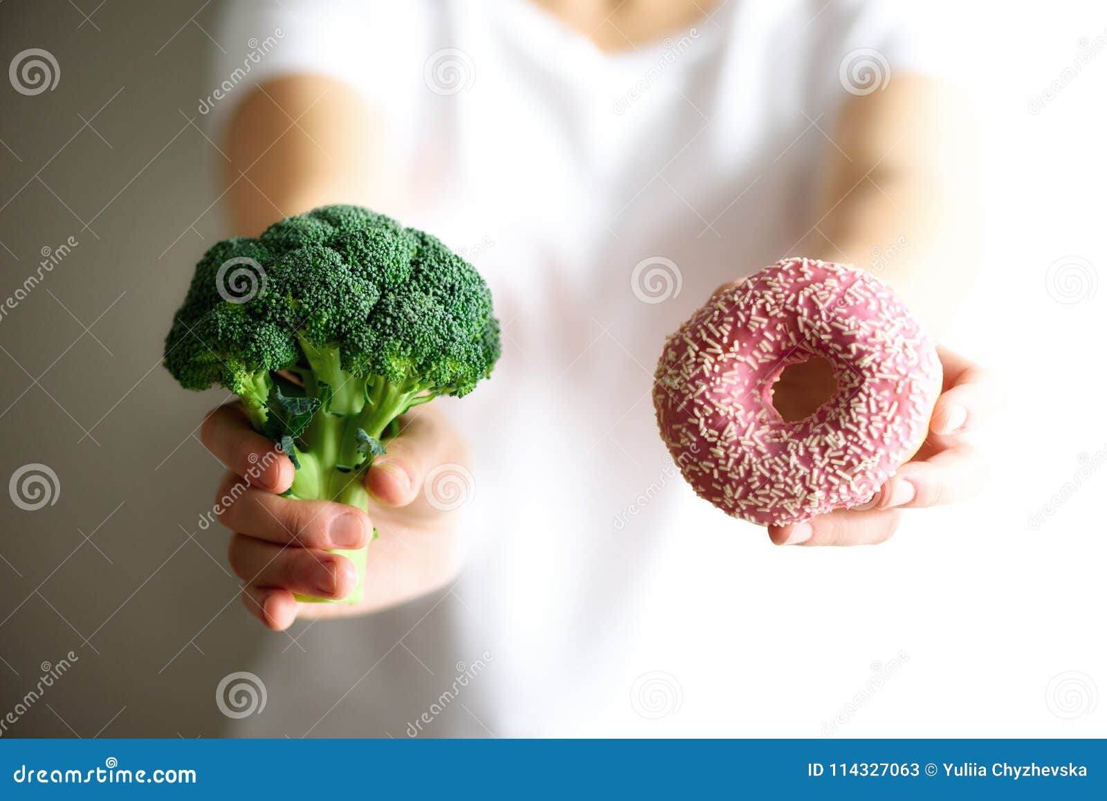 young woman in white t-shirt choosing between broccoli or junk food, donut. healthy clean detox eating concept