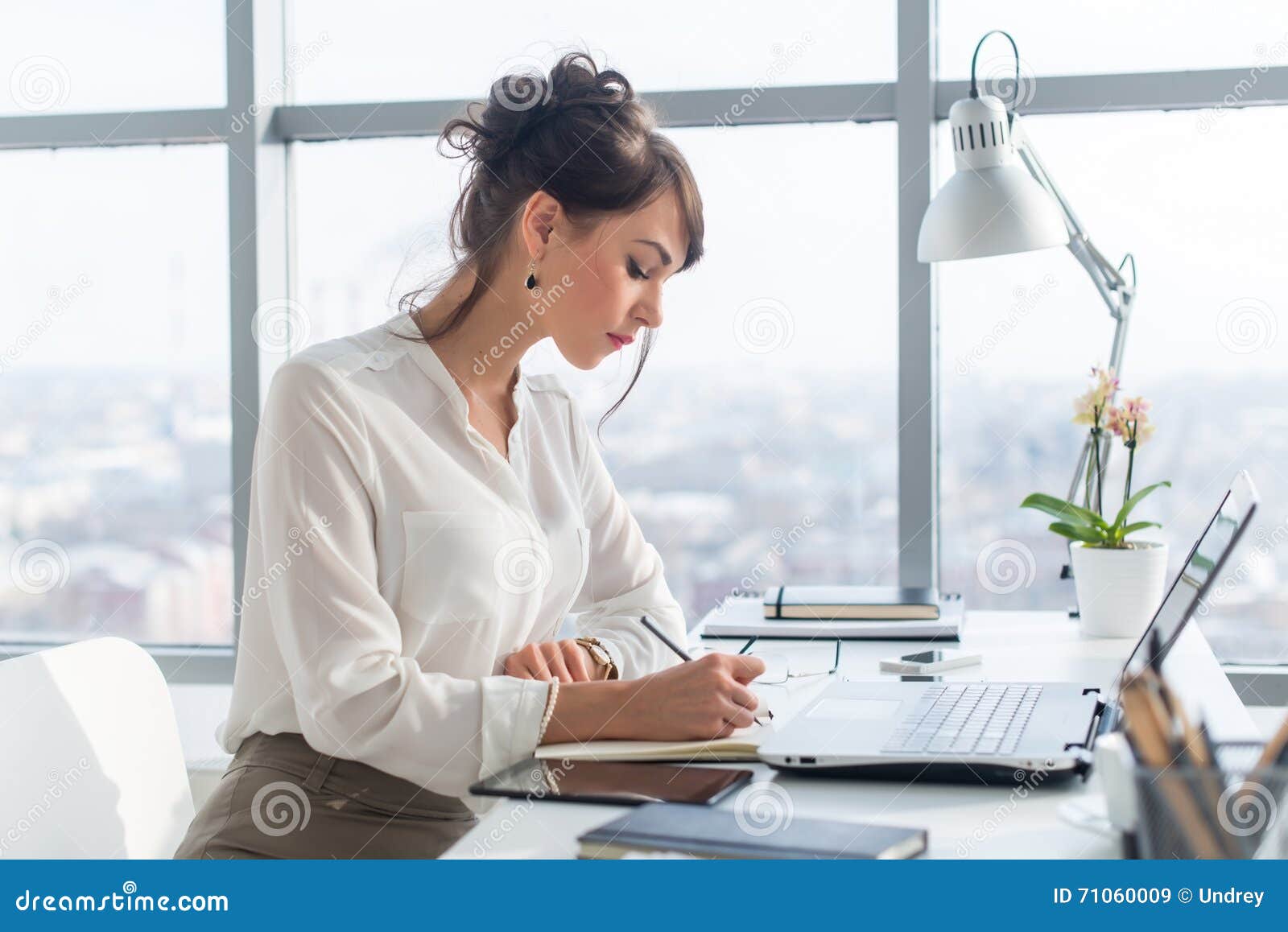 young woman working as an office manager, planning work tasks, writing down her schedule to planner at the workplace.