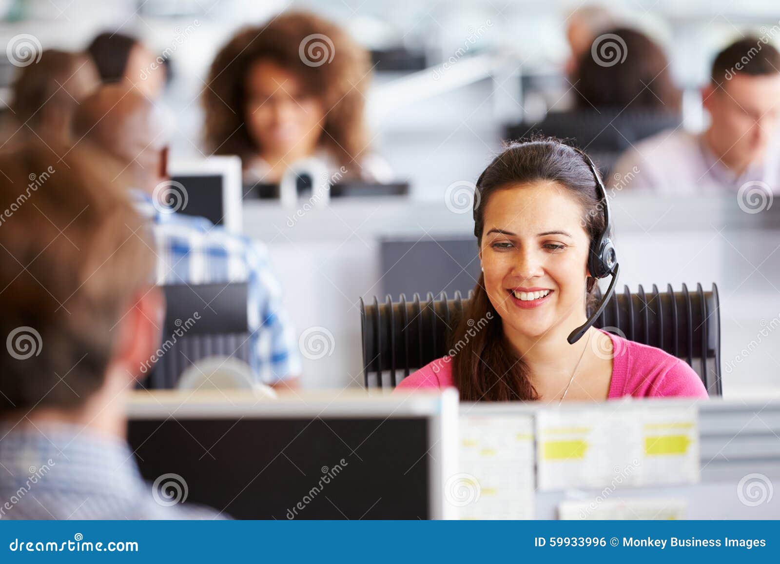 young woman working in call centre, surrounded by colleagues