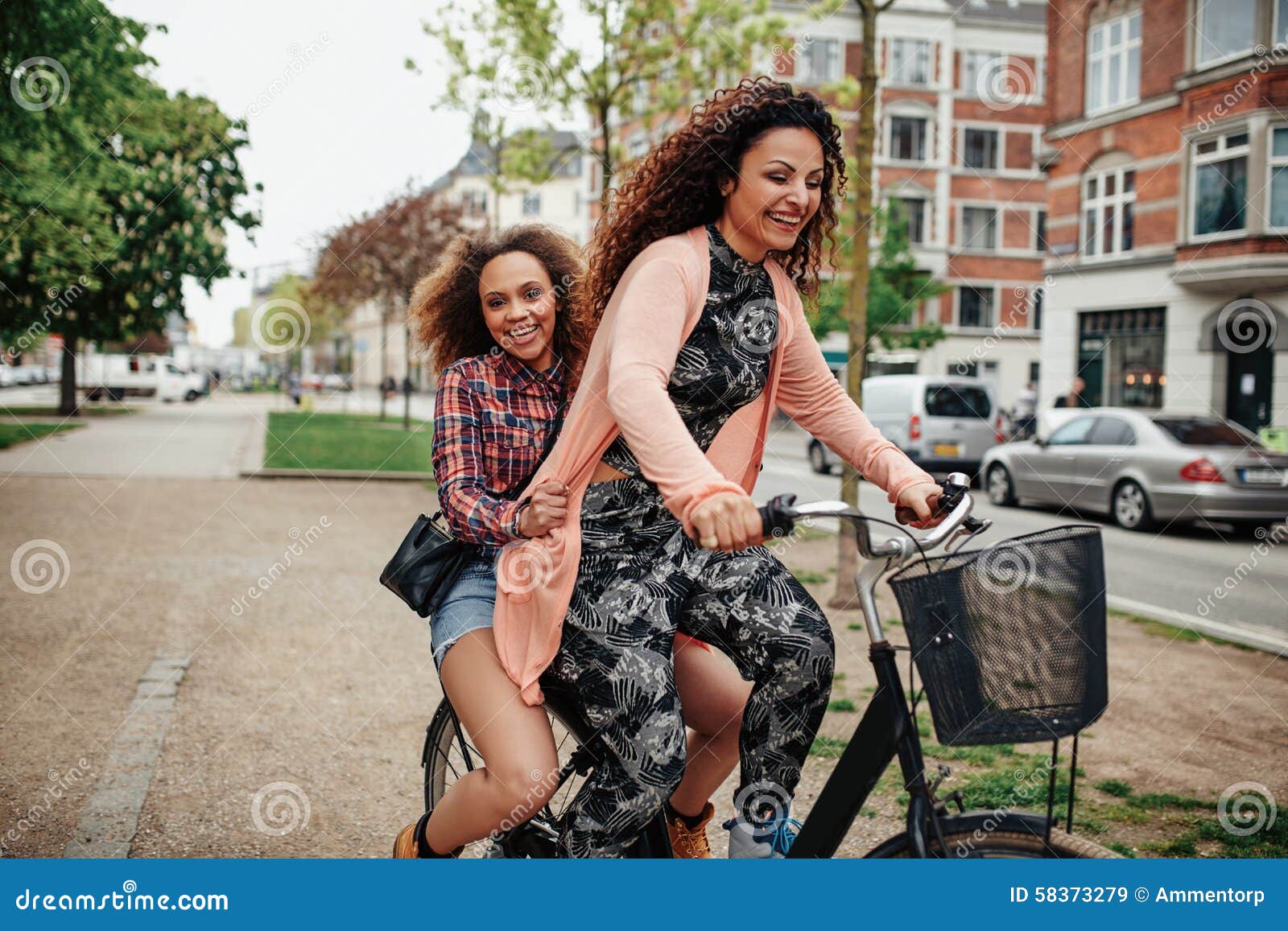 Young Women Enjoying Bicycle Ride on City Street Stock Image - Young Women Enjoying Bicycle RiDe City Street Cheerful Two Girls Together RiDing One 58373279
