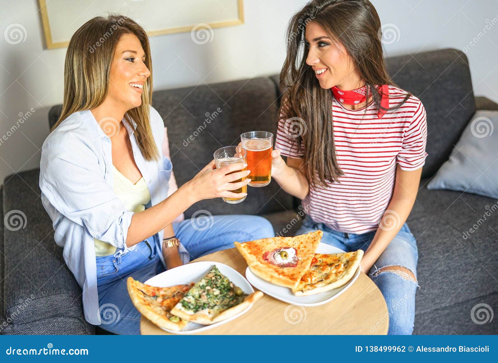Young Women Having A Lunch Together Toasting Beers And Eating