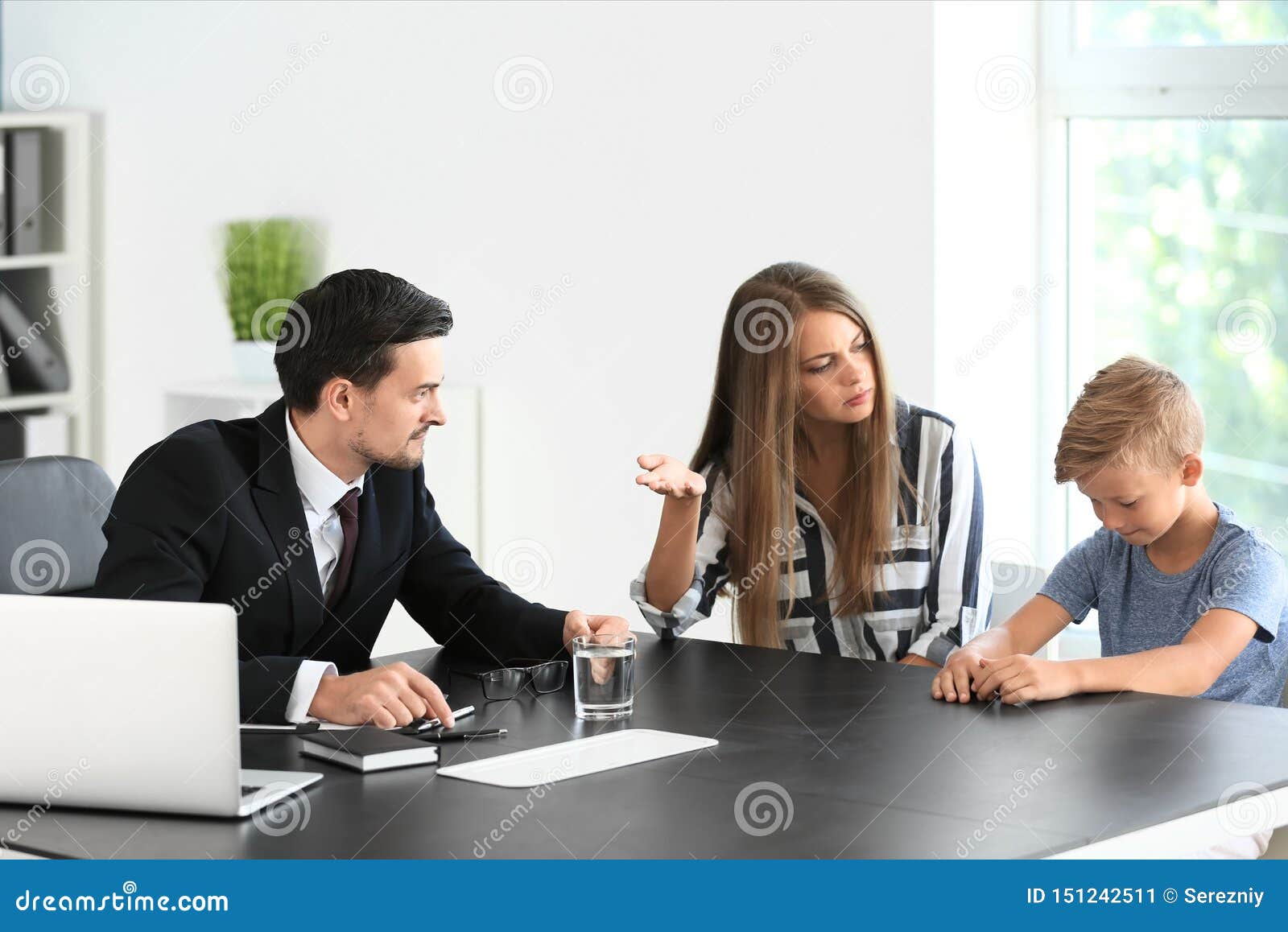 young woman and her son meeting with headmaster at school