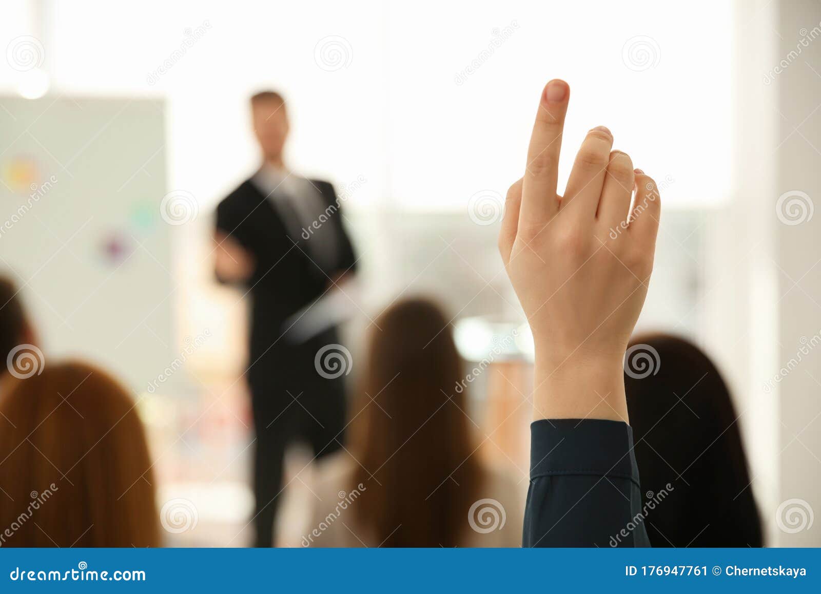 young woman raising hand to ask question at business training, closeup