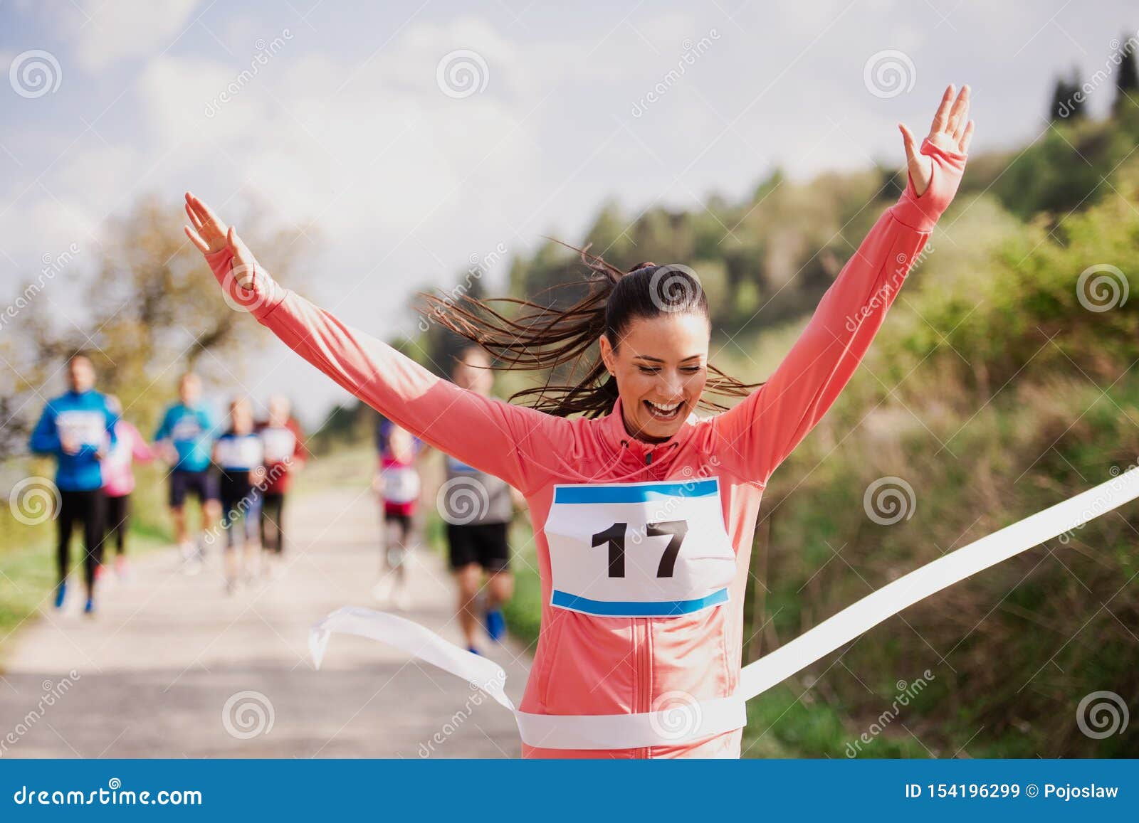 young woman runner crossing finish line in a race competition in nature.