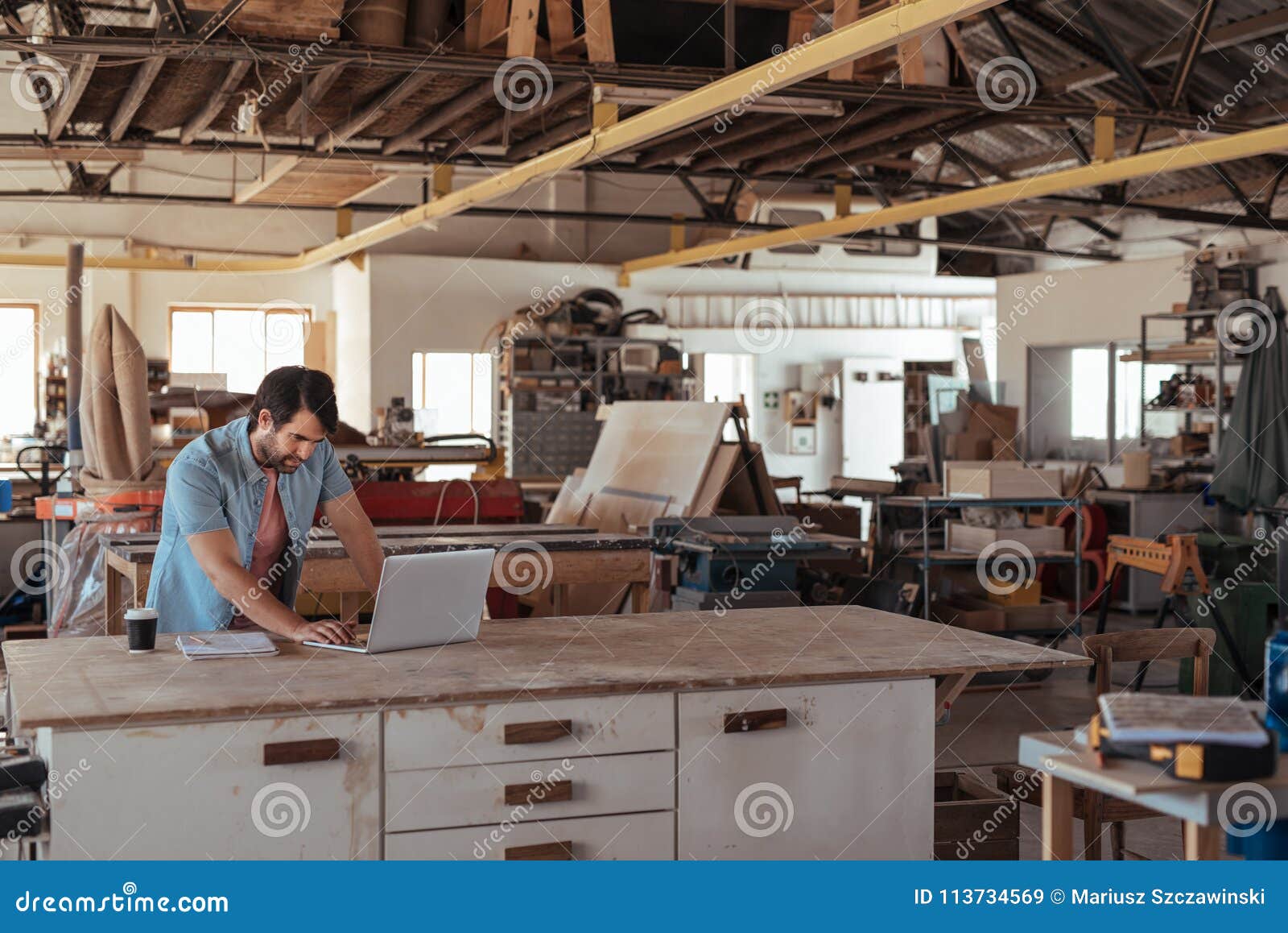 Young Woodworker Working Online at a Bench in His Stock Image