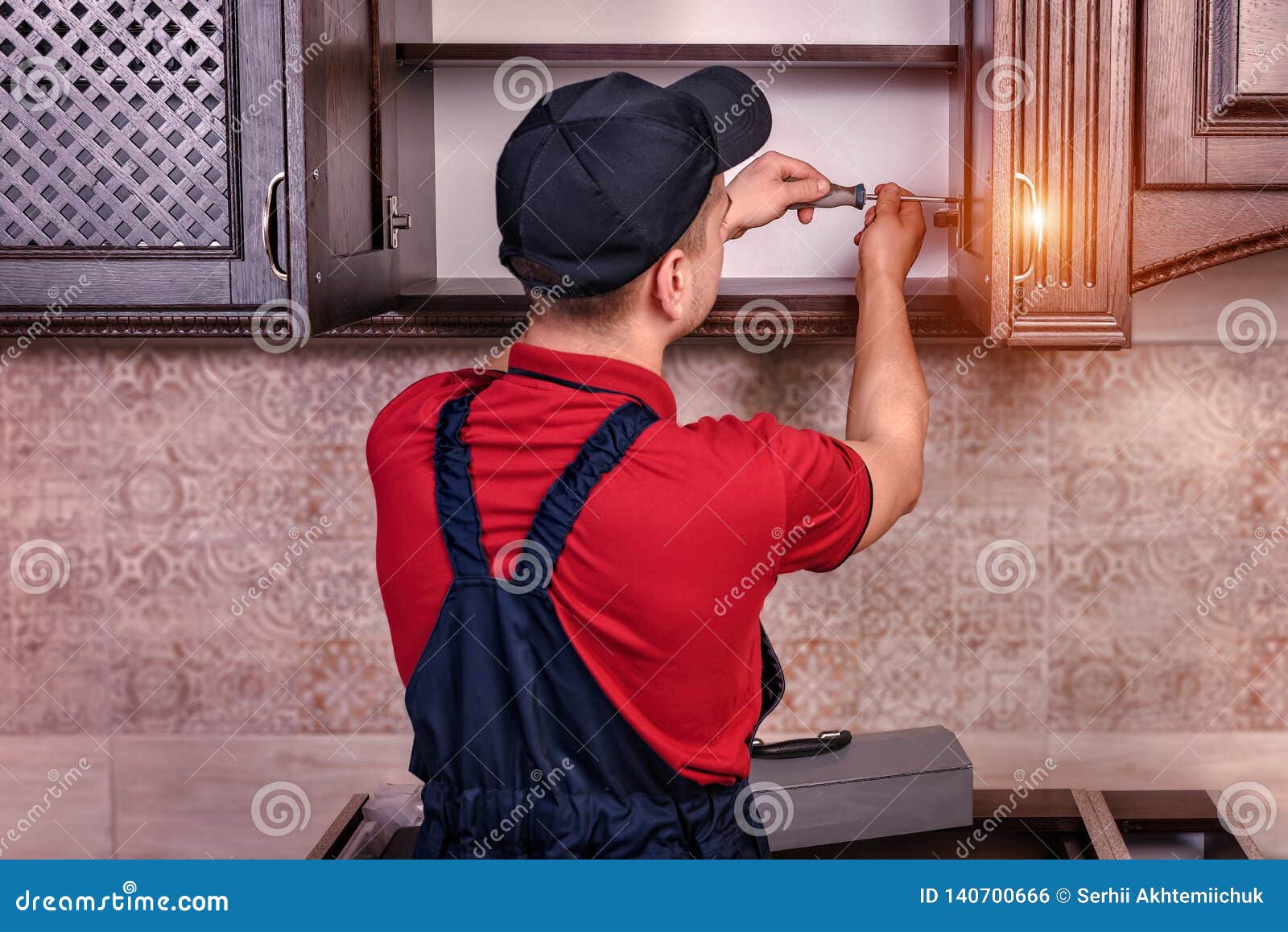 A Young Worker is Assembling Modern Wooden Kitchen Furniture Stock