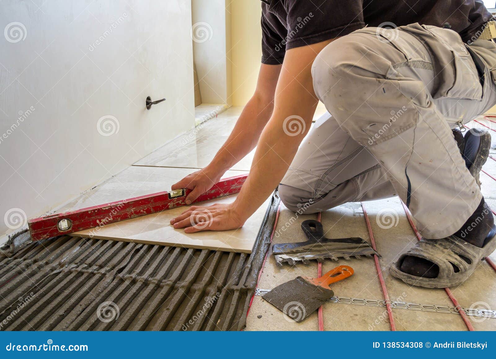 Young Worker Tiler Installing Ceramic Tiles Using Lever On Cement