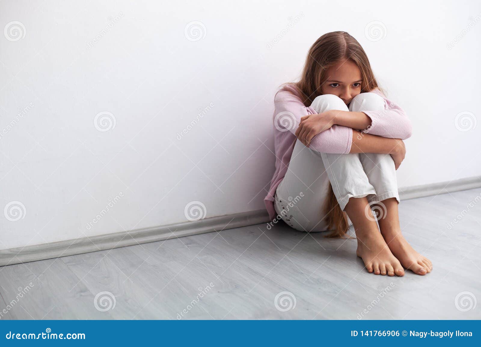 Young Worried Or Sad Girl Sitting On The Floor By The W