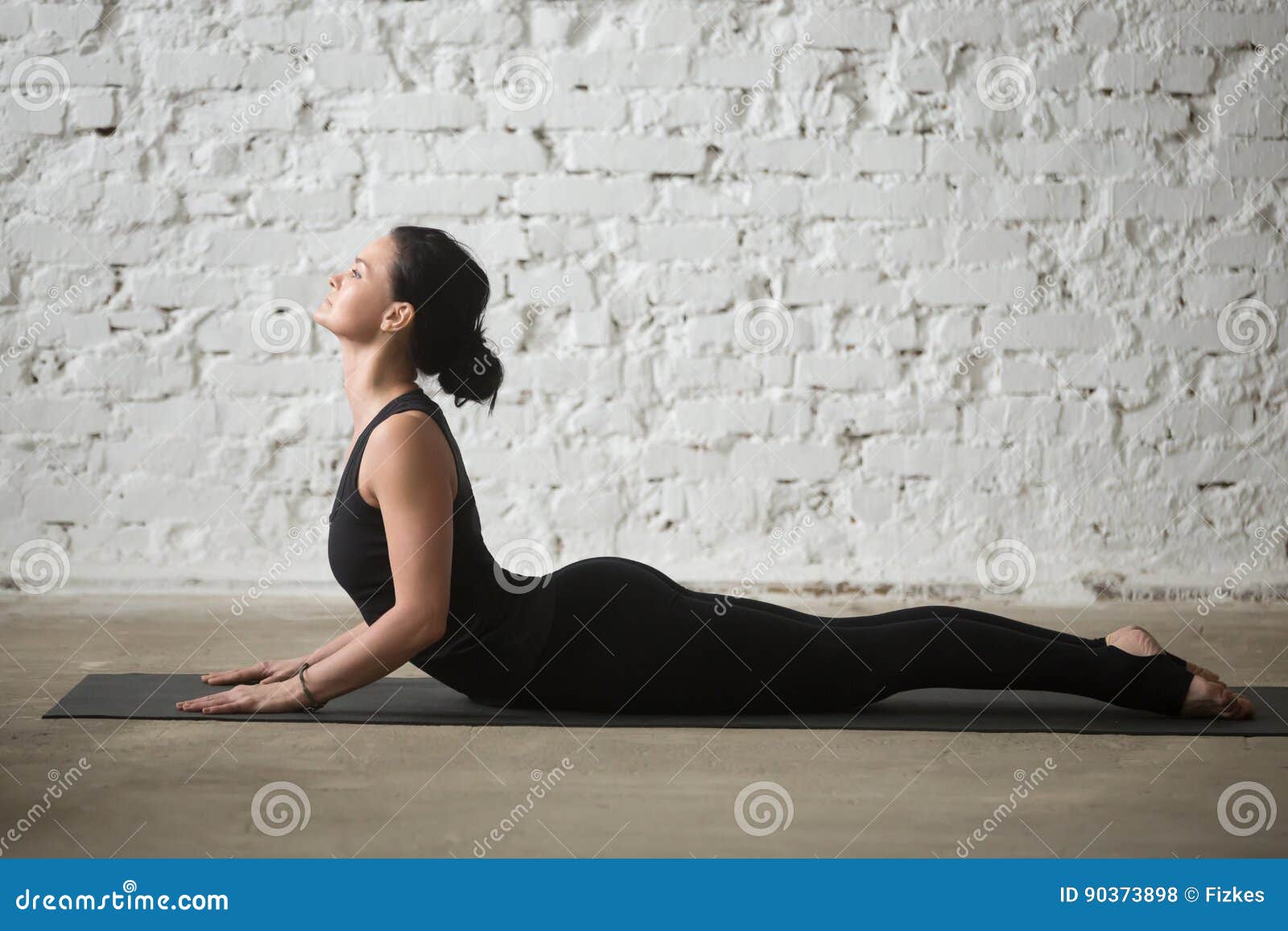 young yogi attractive woman in cobra pose, white loft background