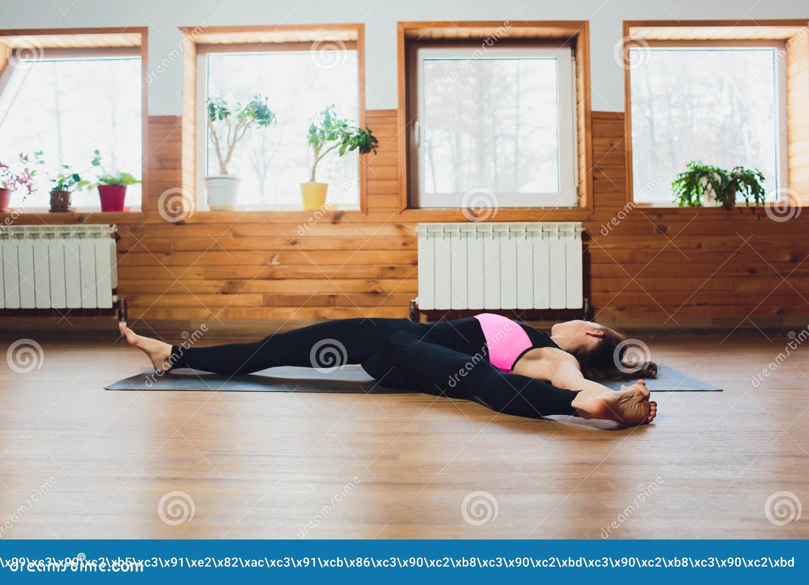 young yogi sporty woman working out, warming up using yogic belt, lying in yoga supta padangushthasana, one leg lift