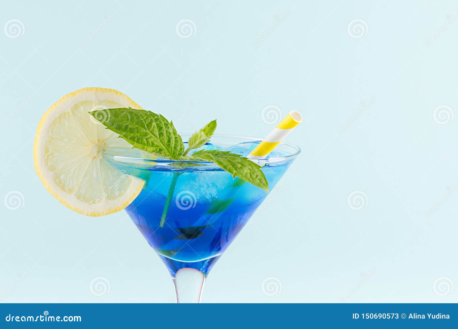 youth fresh alcohol blue hawaii cocktail with licor curacao, ice cube, lemon slice, yellow straw in wine glass on mint background.