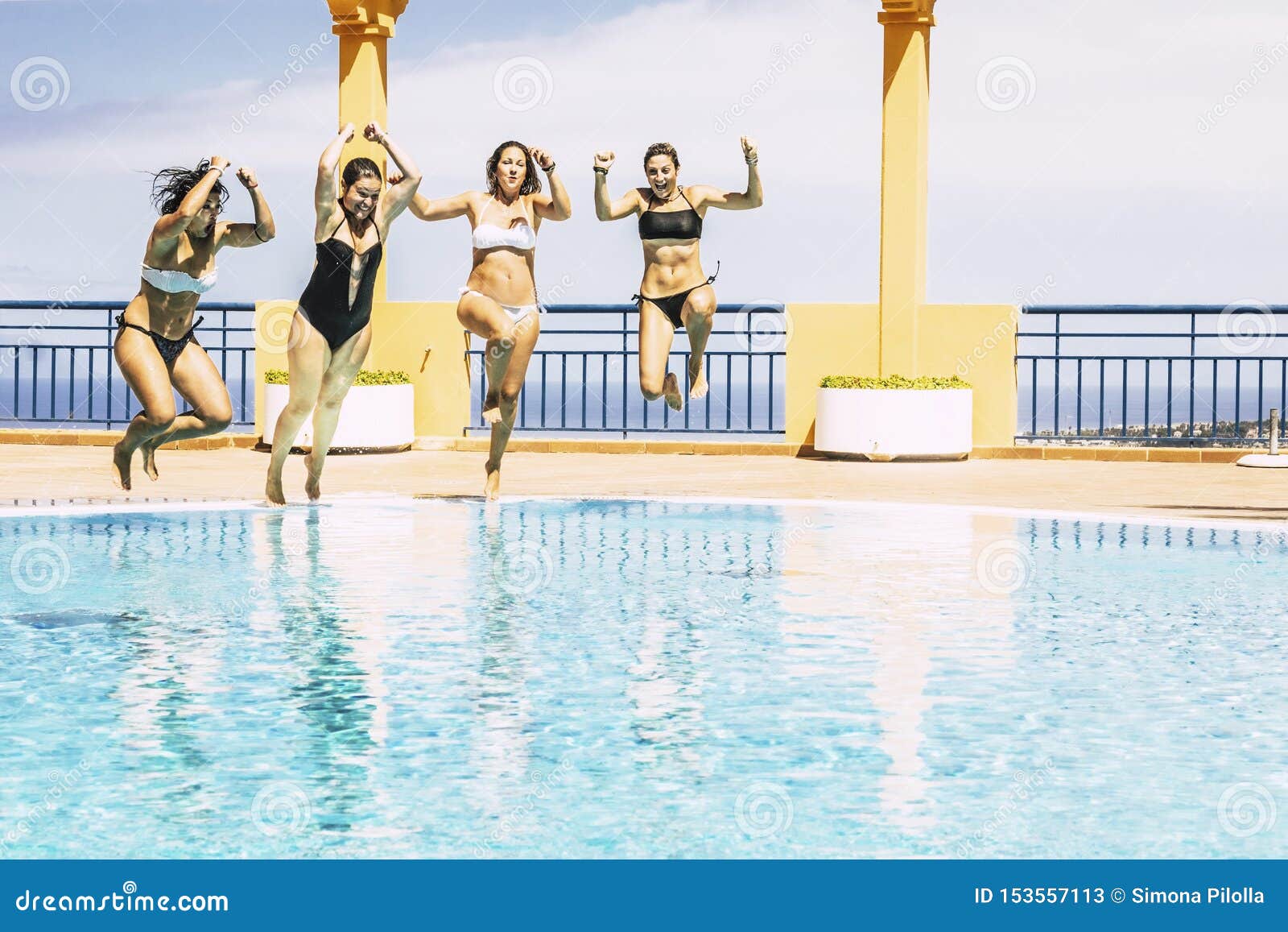 youthful happy young people jumping together in the swimming pool enjoying the summer holiday vaction season - friends hace fun